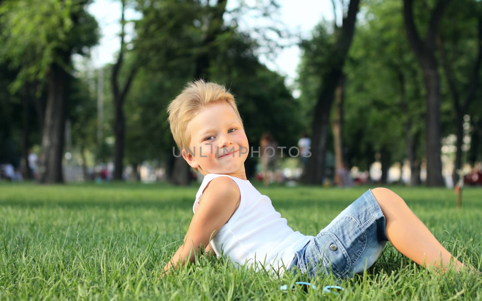 Little boy sitting in the park on a grass