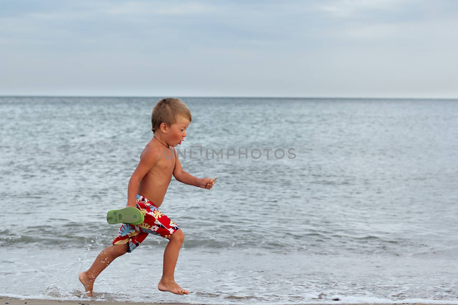 Little boy running at the shore near the sea