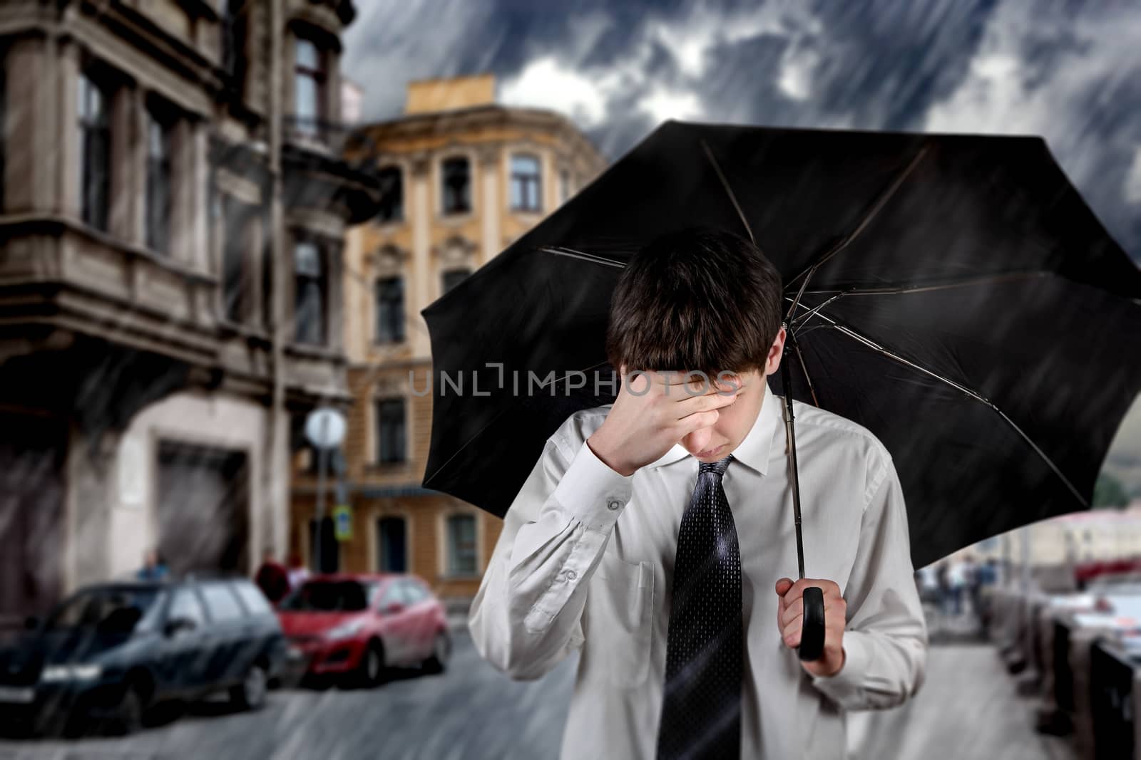 Sad Young Man walking with Umbrella under the Rain in the City