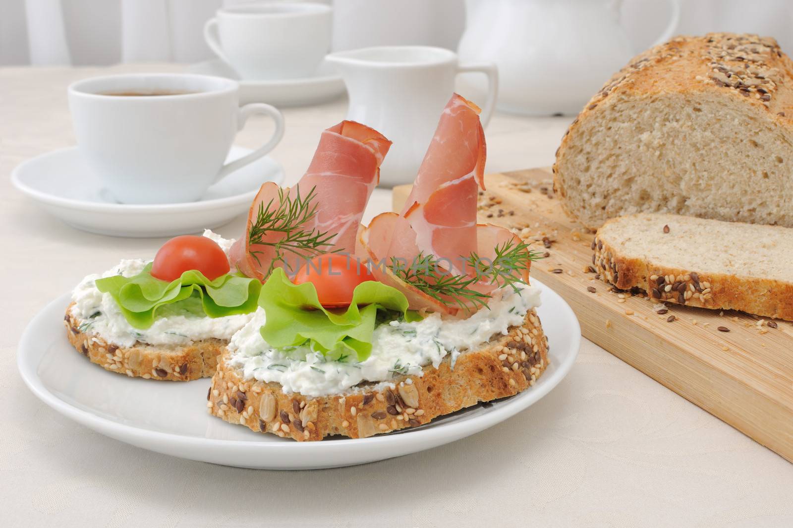 breakfast with a cup of coffee and a sandwich of whole grain bread with ricotta and ham

