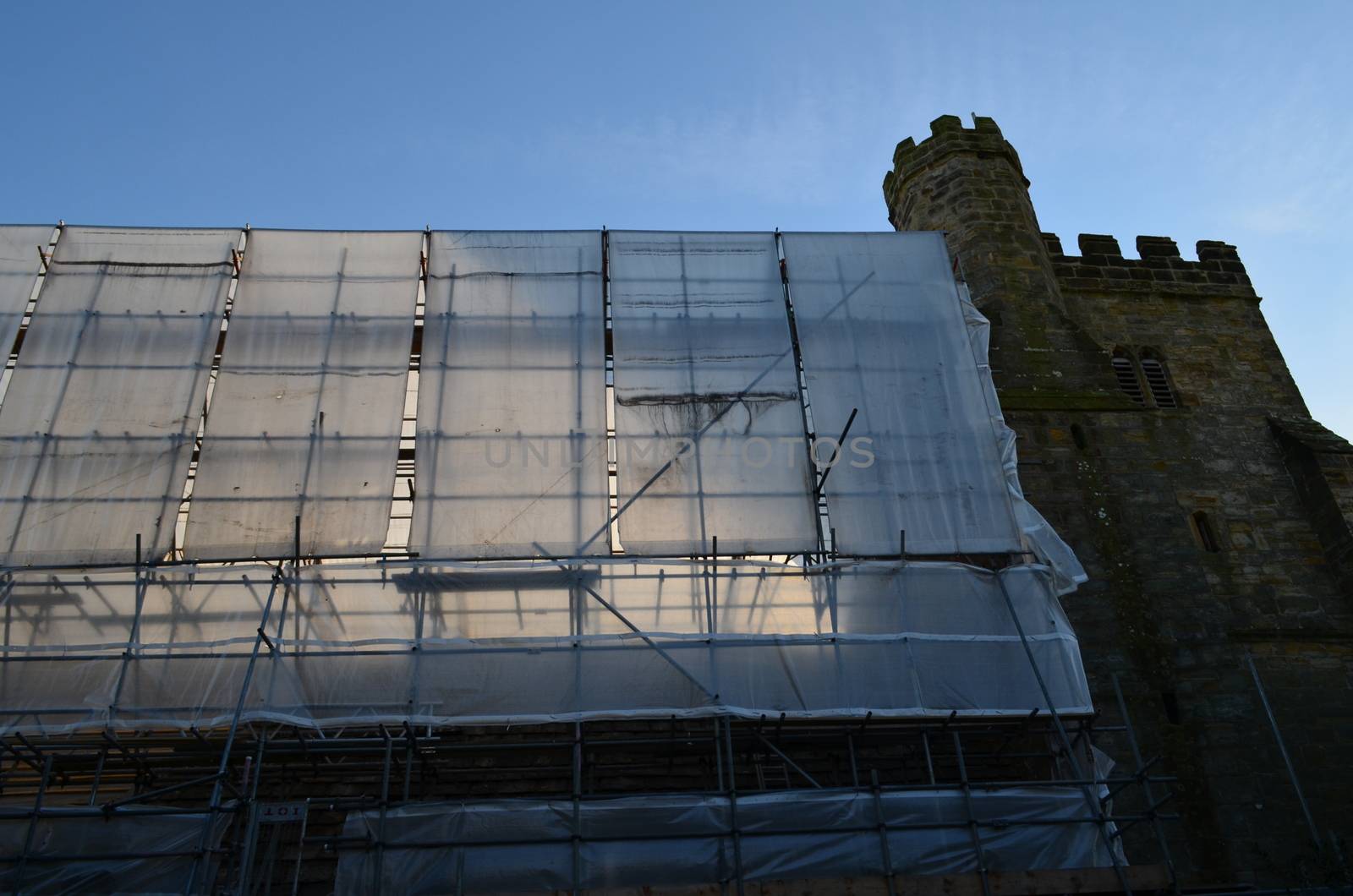 A building having restoration work carried out under a large framework of scaffolding and plastic sheeting.