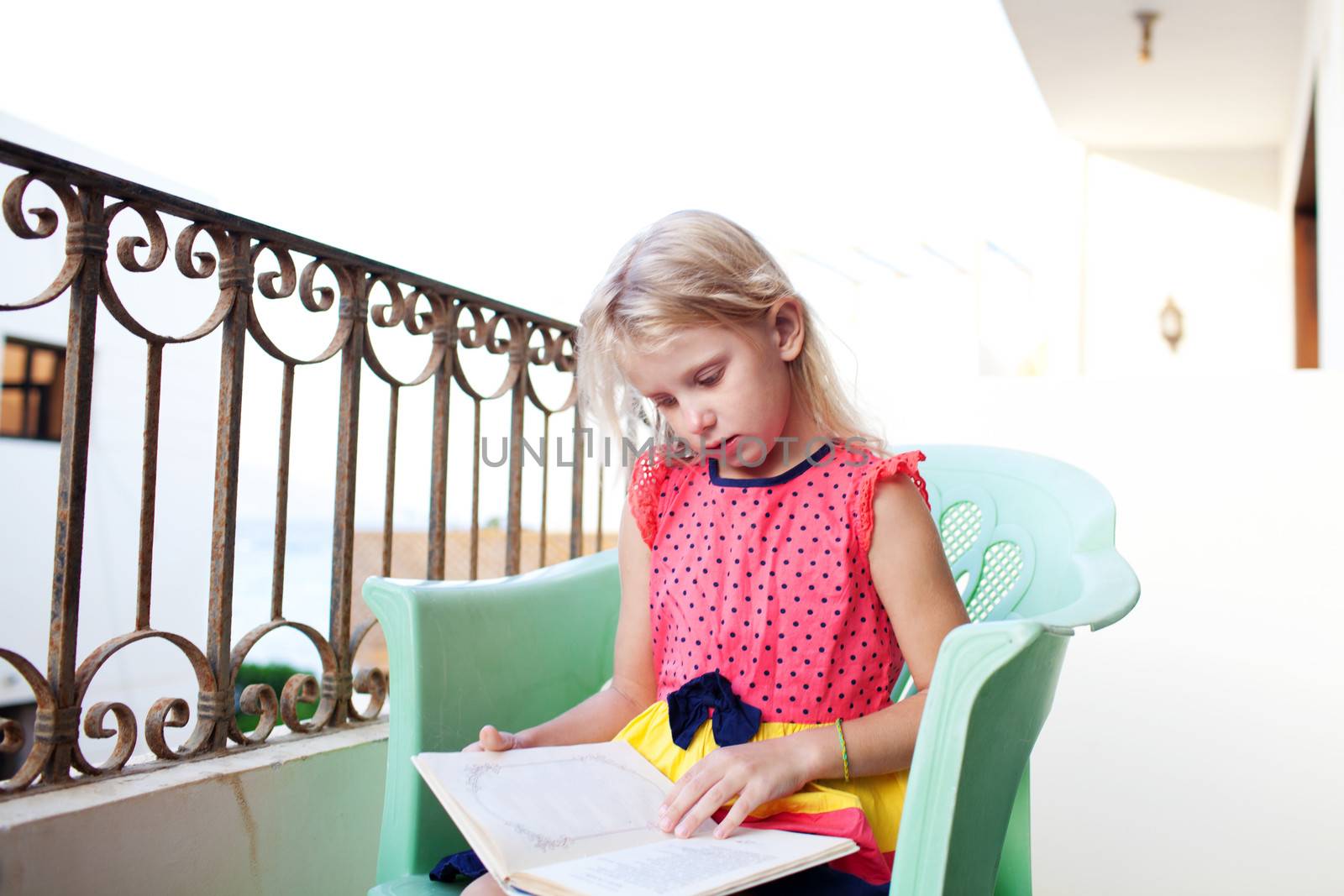 small girl reading on the balcony by vsurkov