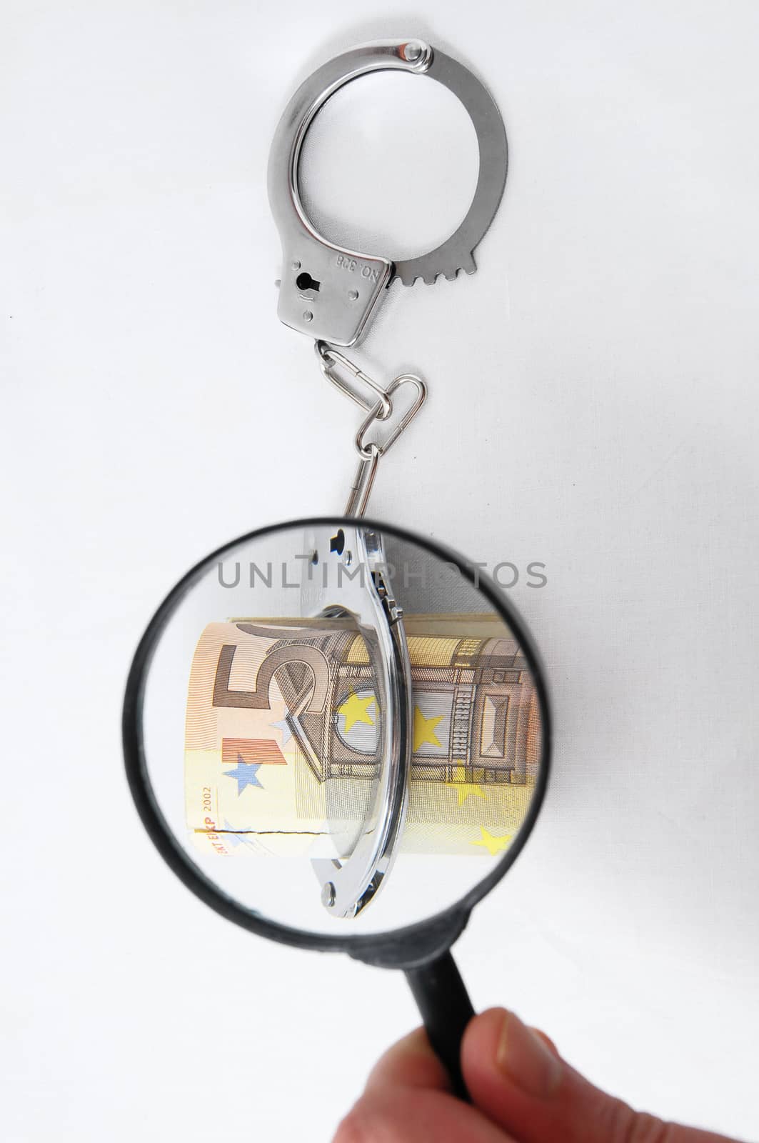 Financial Concept Loupe, Handcuffs and Money on a White Background