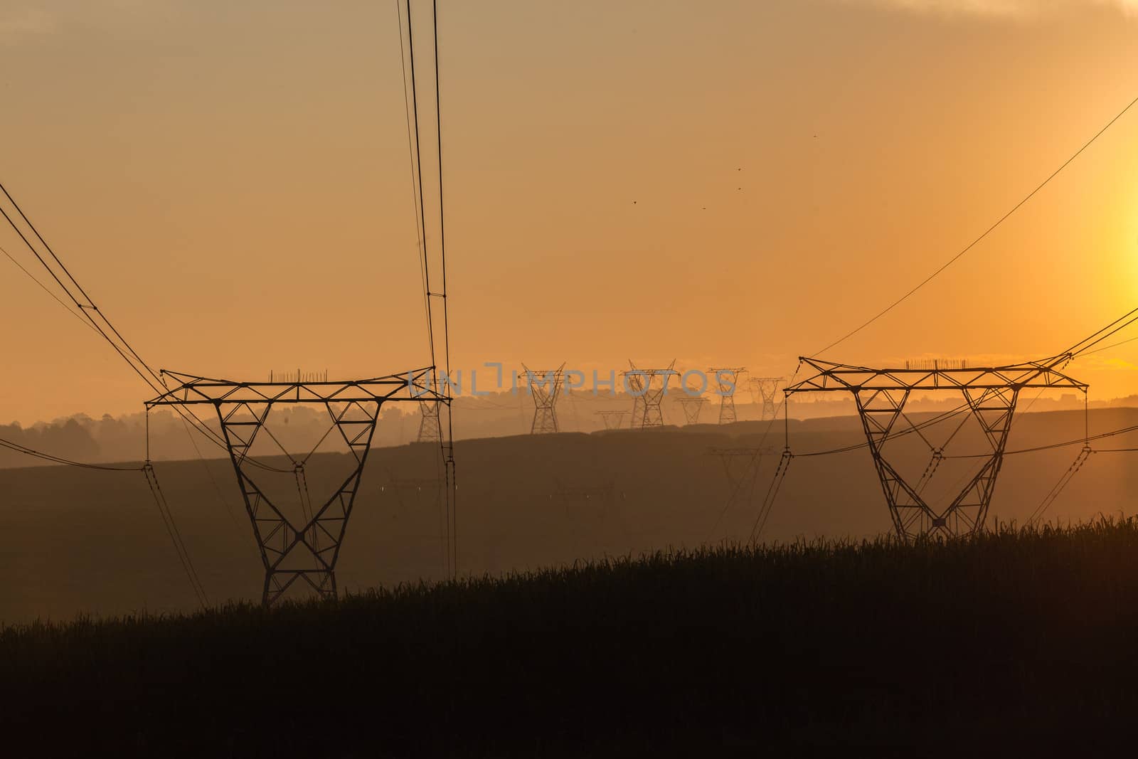 Electricity cables attached to steel structure towers transport electrical power supply over the countryside landscape