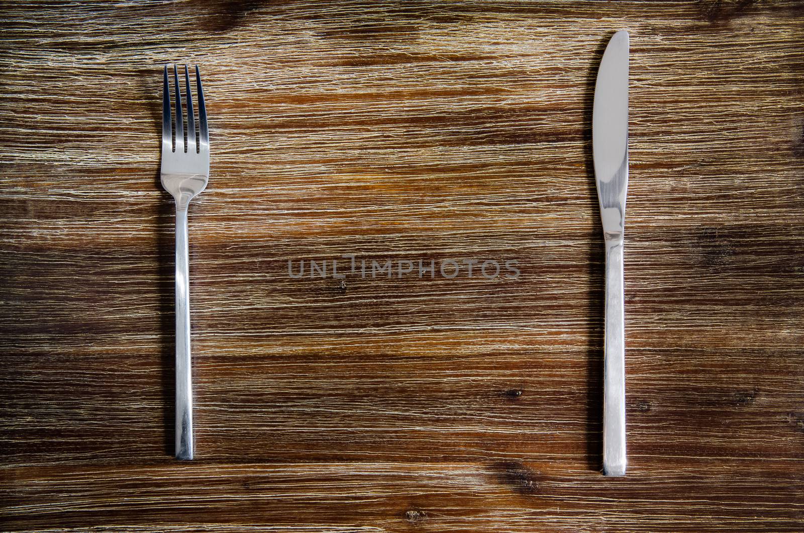 Knife and fork set on a wooden table by martinm303