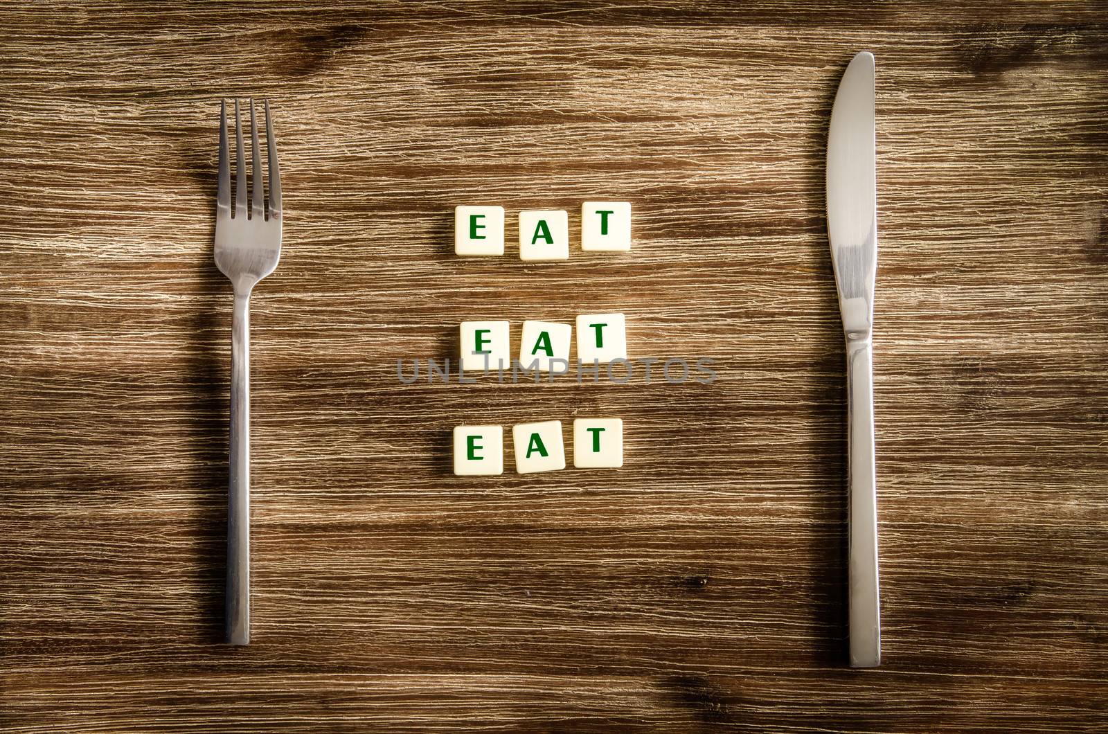 Knife and fork set on wooden table, sign saying Eat by martinm303