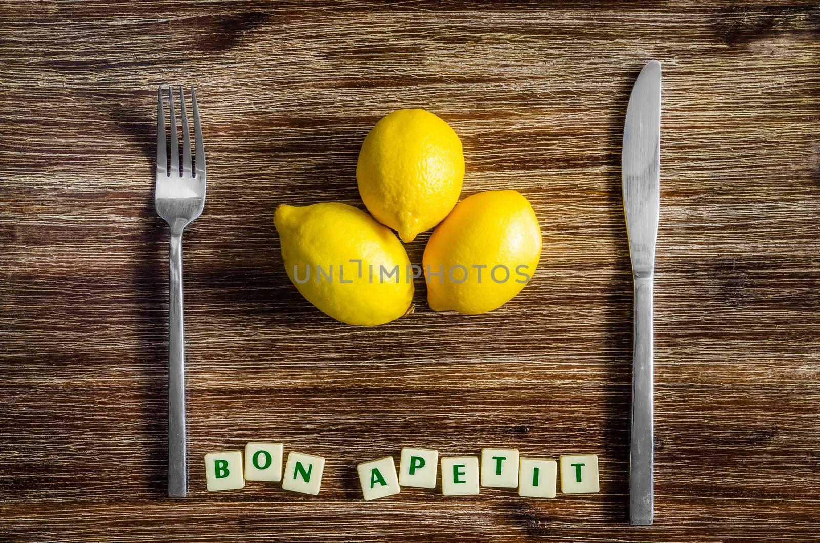 Silverware and lemons on wooden table with Bon apetit sign by martinm303