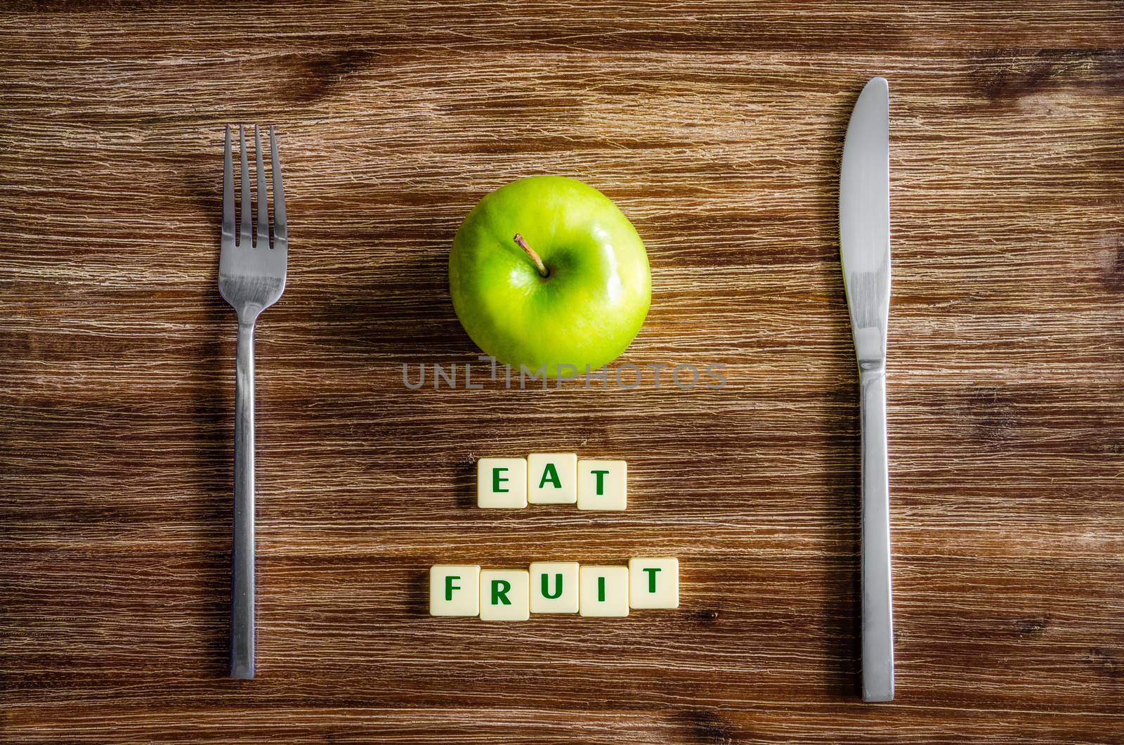 Silverware and apple on wooden table with sign Eat fruit by martinm303