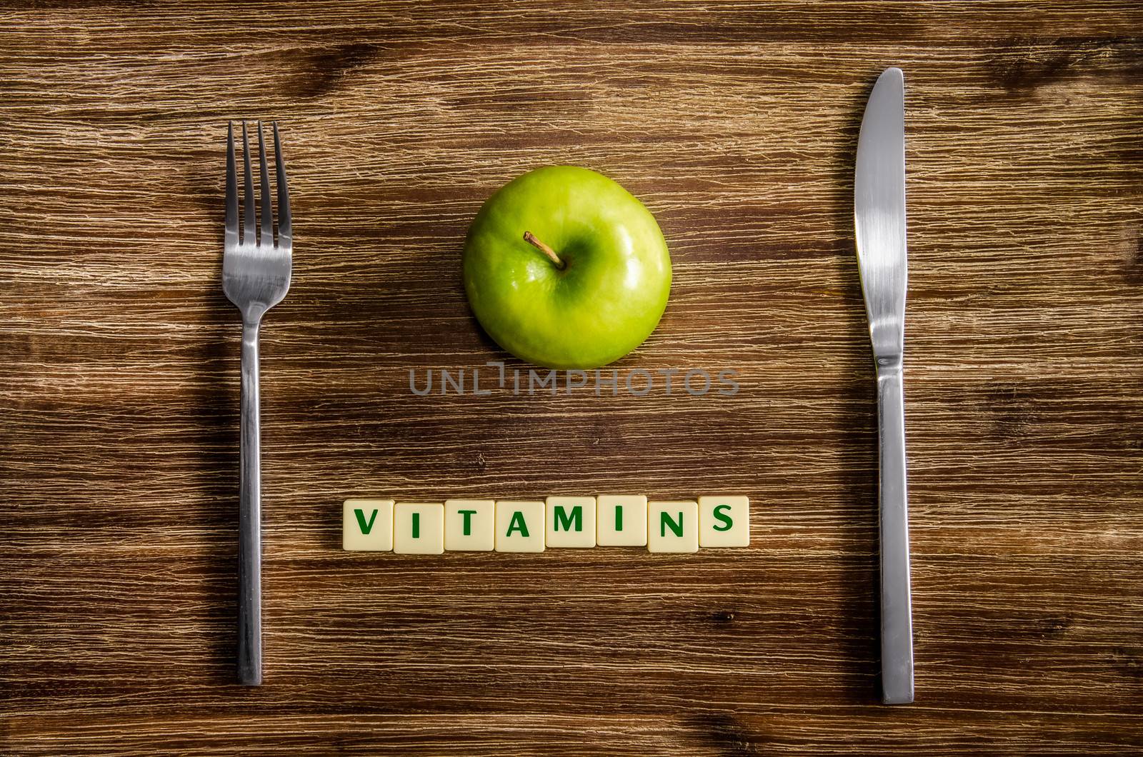 Silverware and apple set on wooden vintage table with sign Vitamins