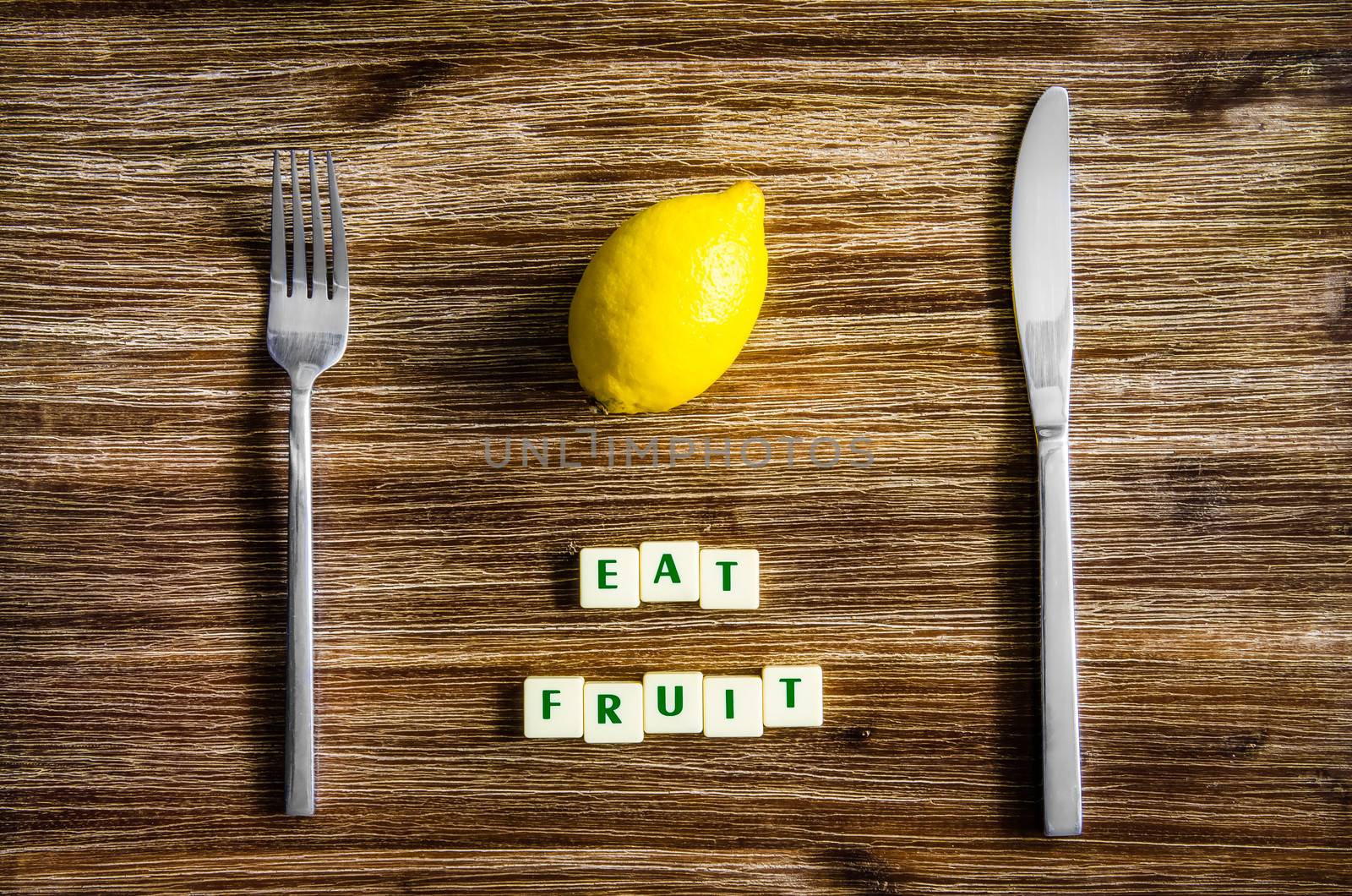 Silverware and lemon on wooden table with sign Eat fruit by martinm303
