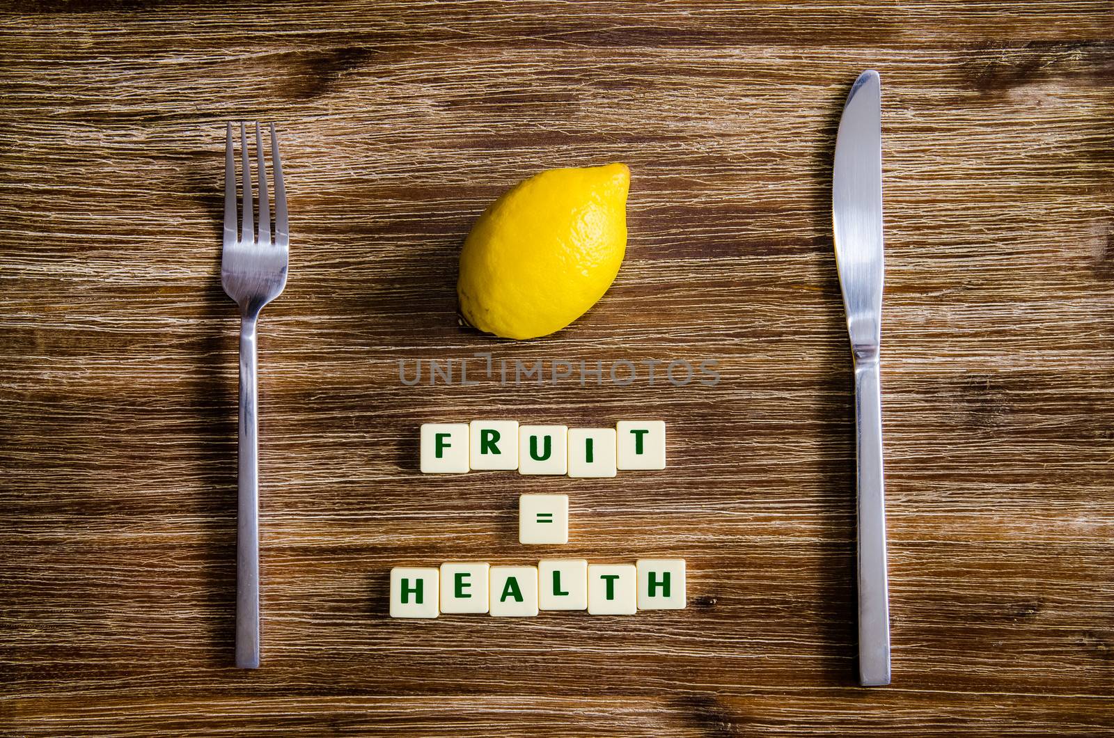 Silverware and lemon set on wooden table with sign saying Fruit equals health