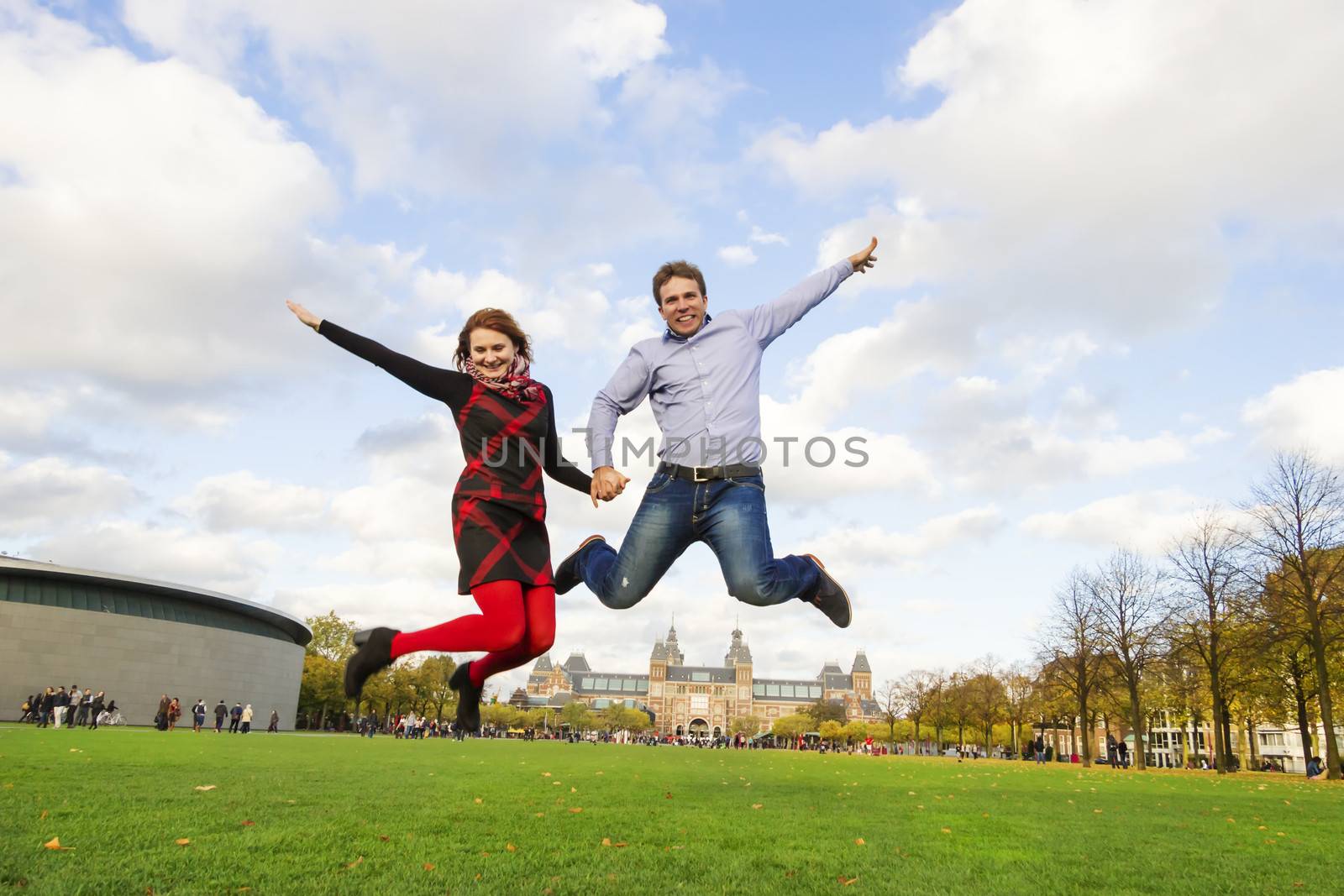 Outdoor happy couple jumping in Museumplein, Amsterdam by Tetyana