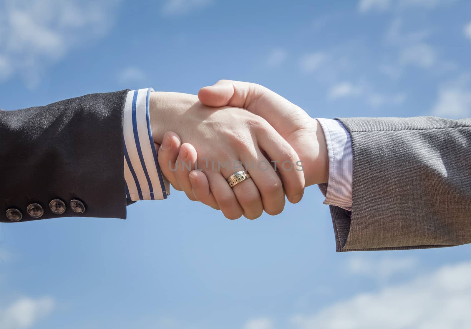 Closeup of a business handshake over blue sky background