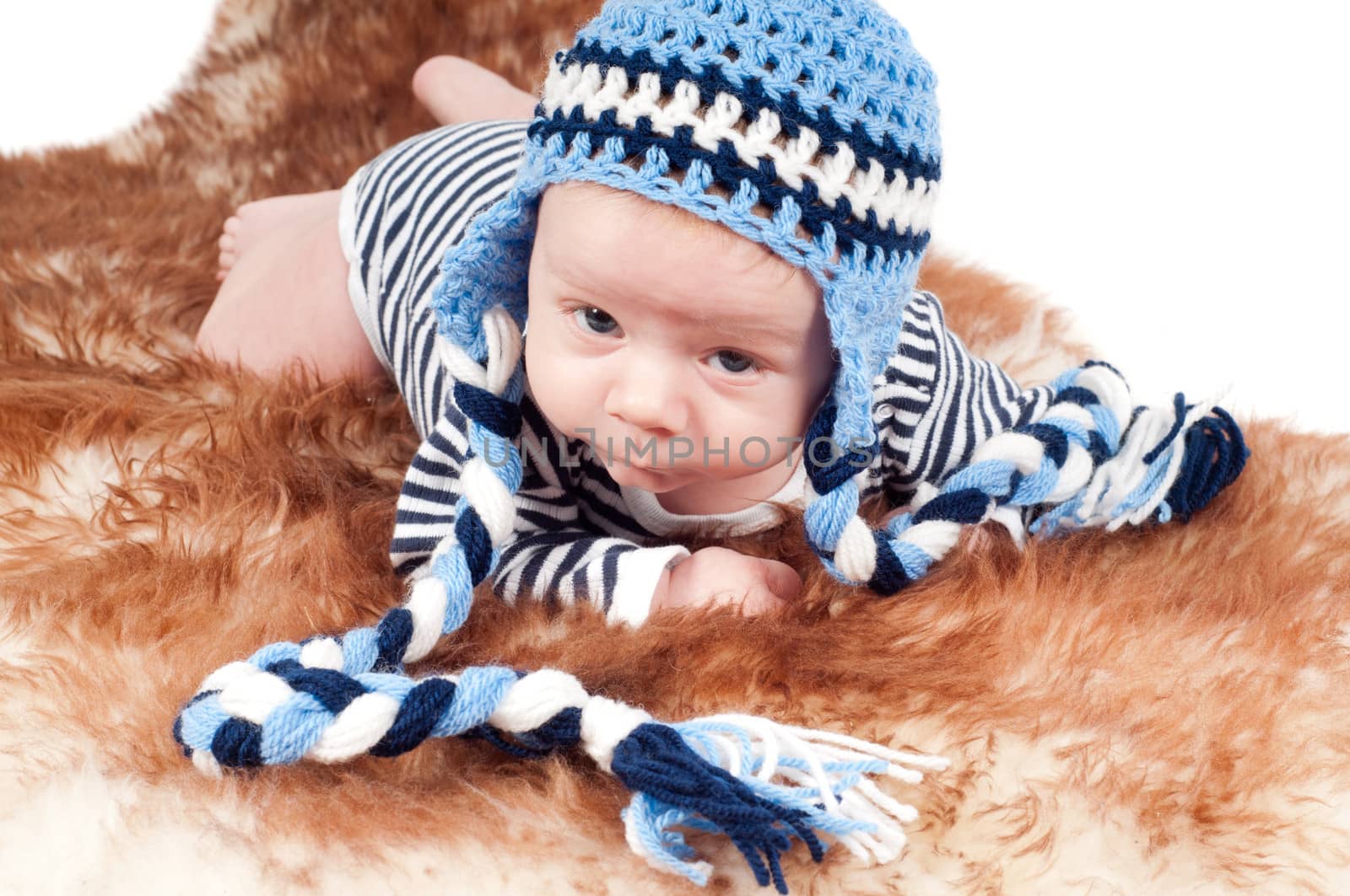 Shot of newborn baby in funny hat lying on fur