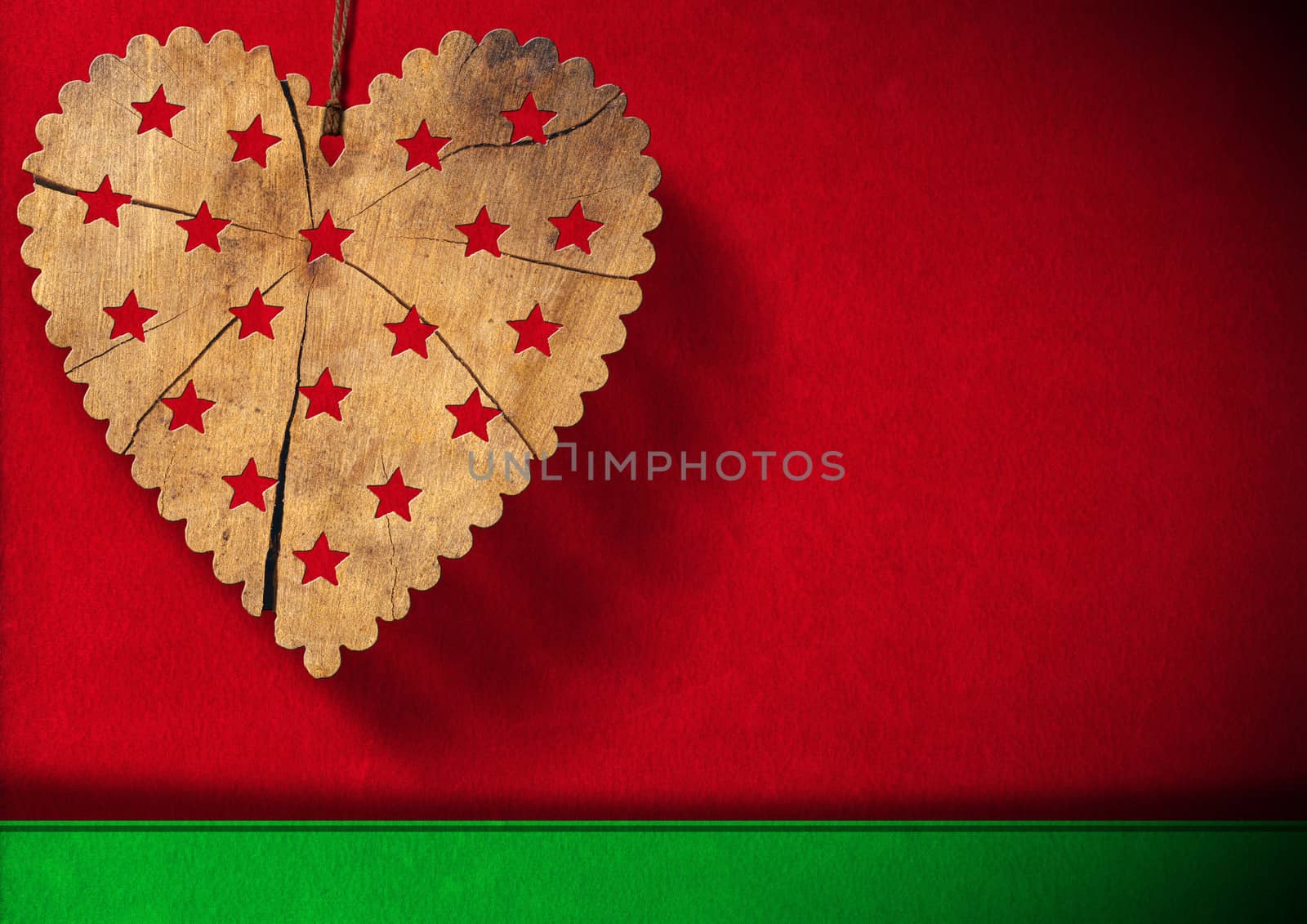 Wooden heart with stars hanging on red and green velvet background with shadows