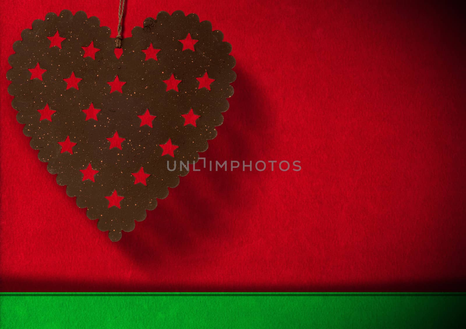Metal heart with stars hanging on red and green velvet background with shadows