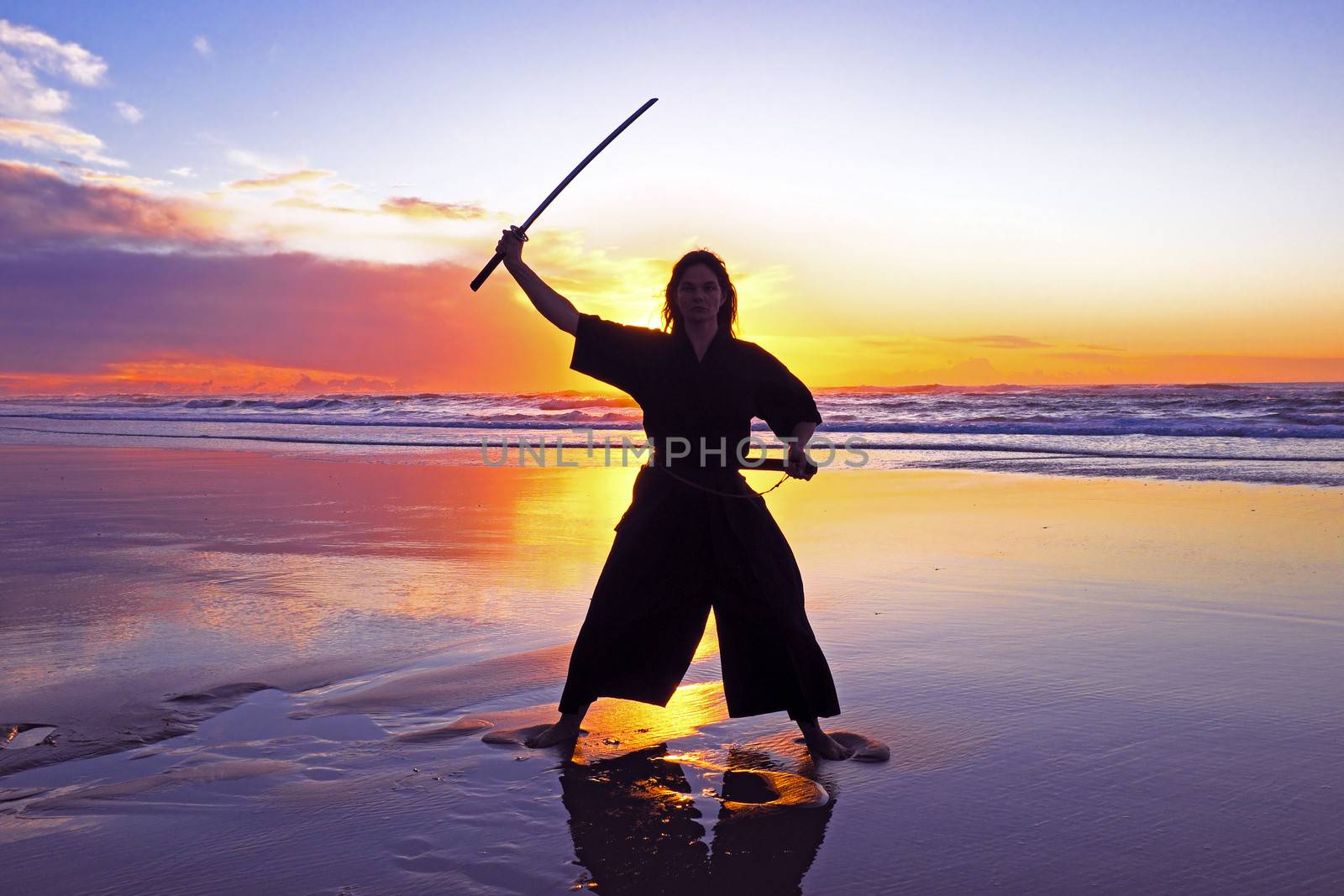 Young samurai women with Japanese sword(Katana) at sunset on the beach