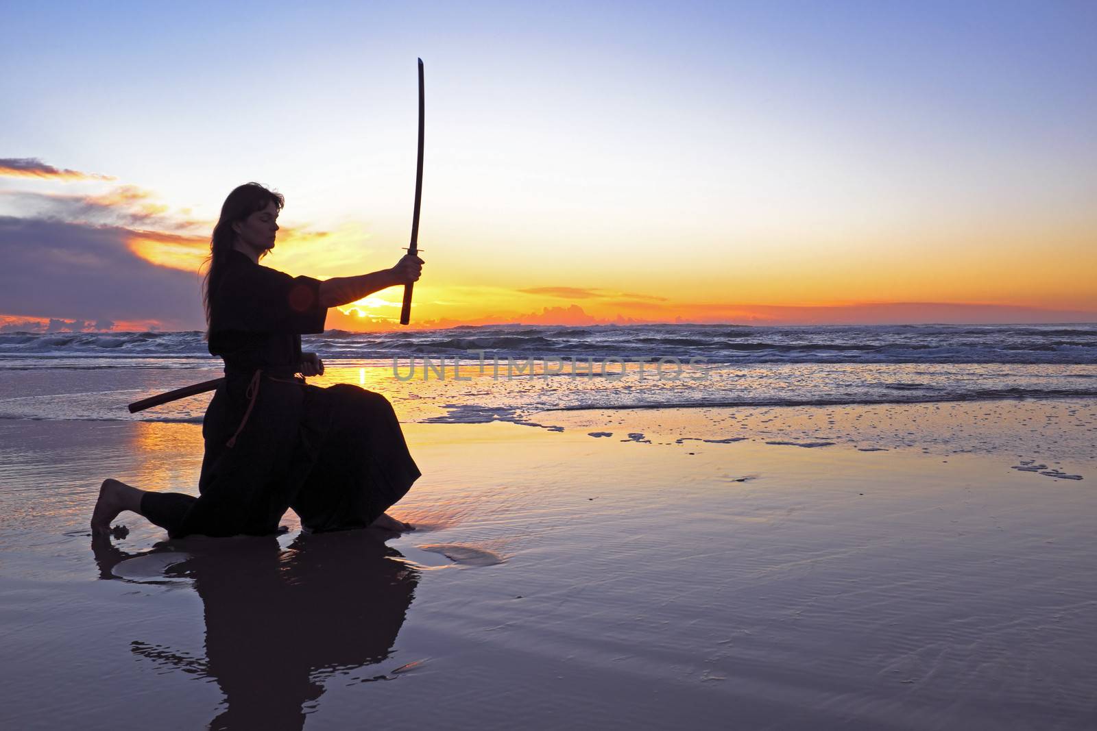 Young samurai women with Japanese sword(Katana) at sunset on the beach