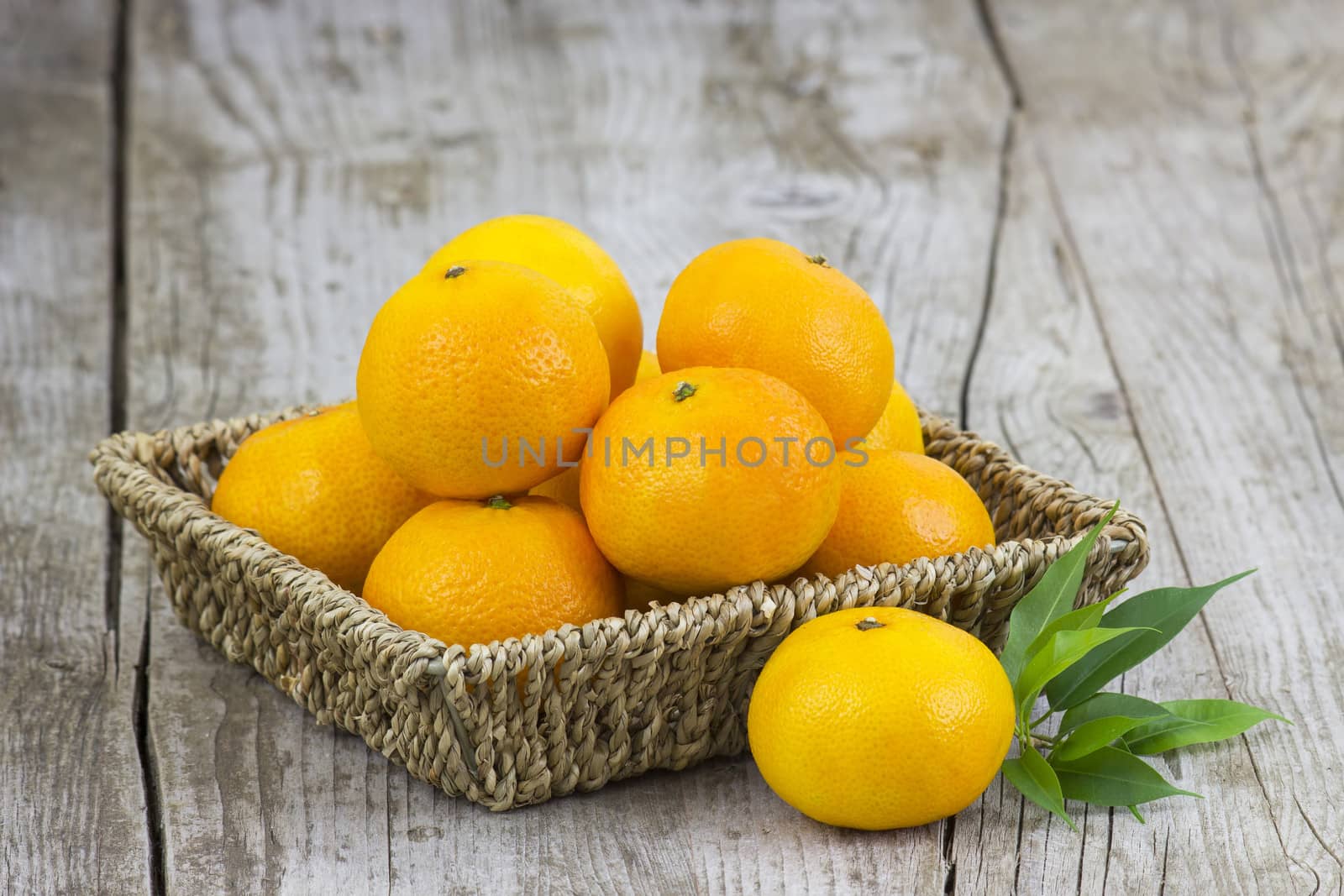 fresh tangerines in a basket on old wooden background