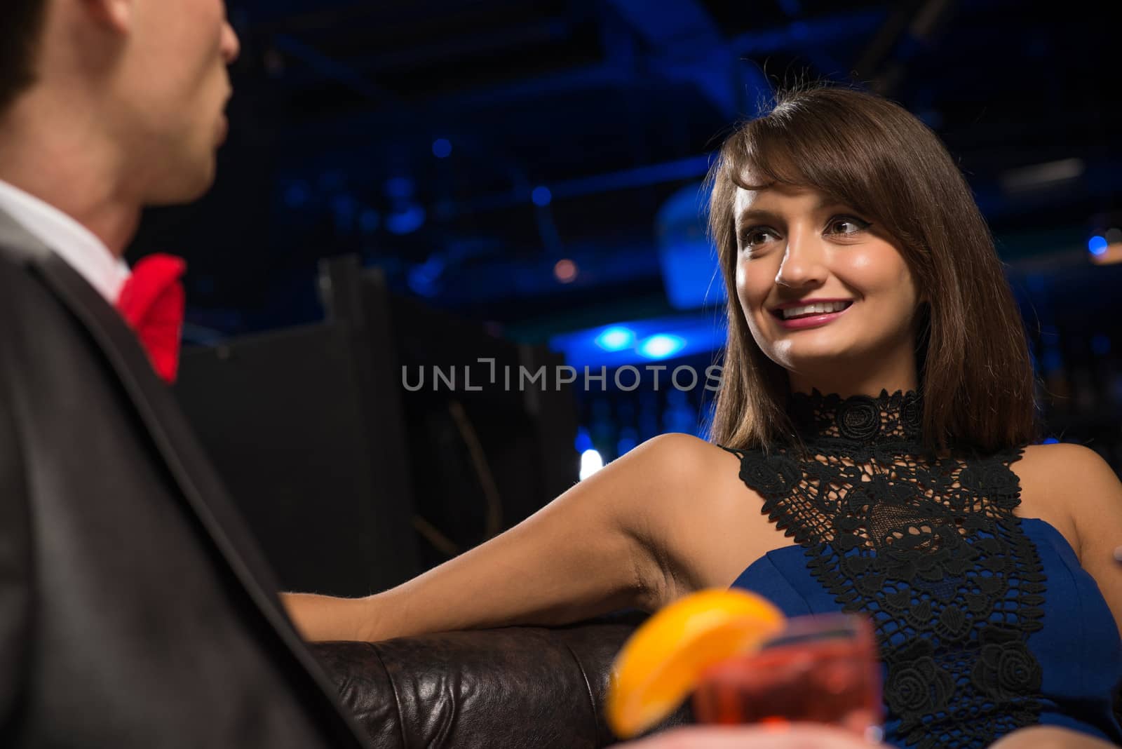 portrait of a woman in a nightclub, sitting on the couch and talking with man