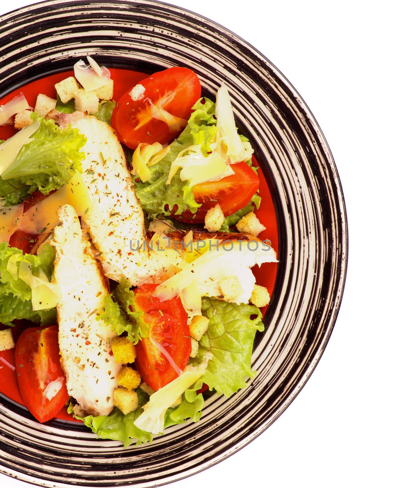 Caesar Salad with Grilled Chicken Breast, Garlic Crouton, Lettuce, Tomatoes and Grated Parmesan Cheese closeup on Striped Plate. Top View