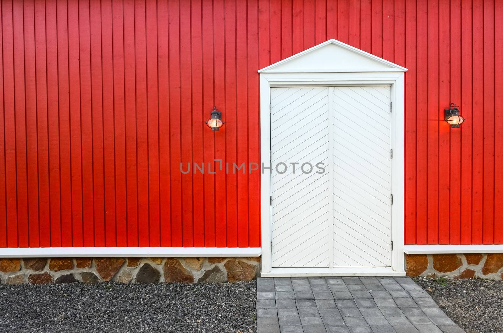 Red wooden wall and frnt white doors with two porch lamps