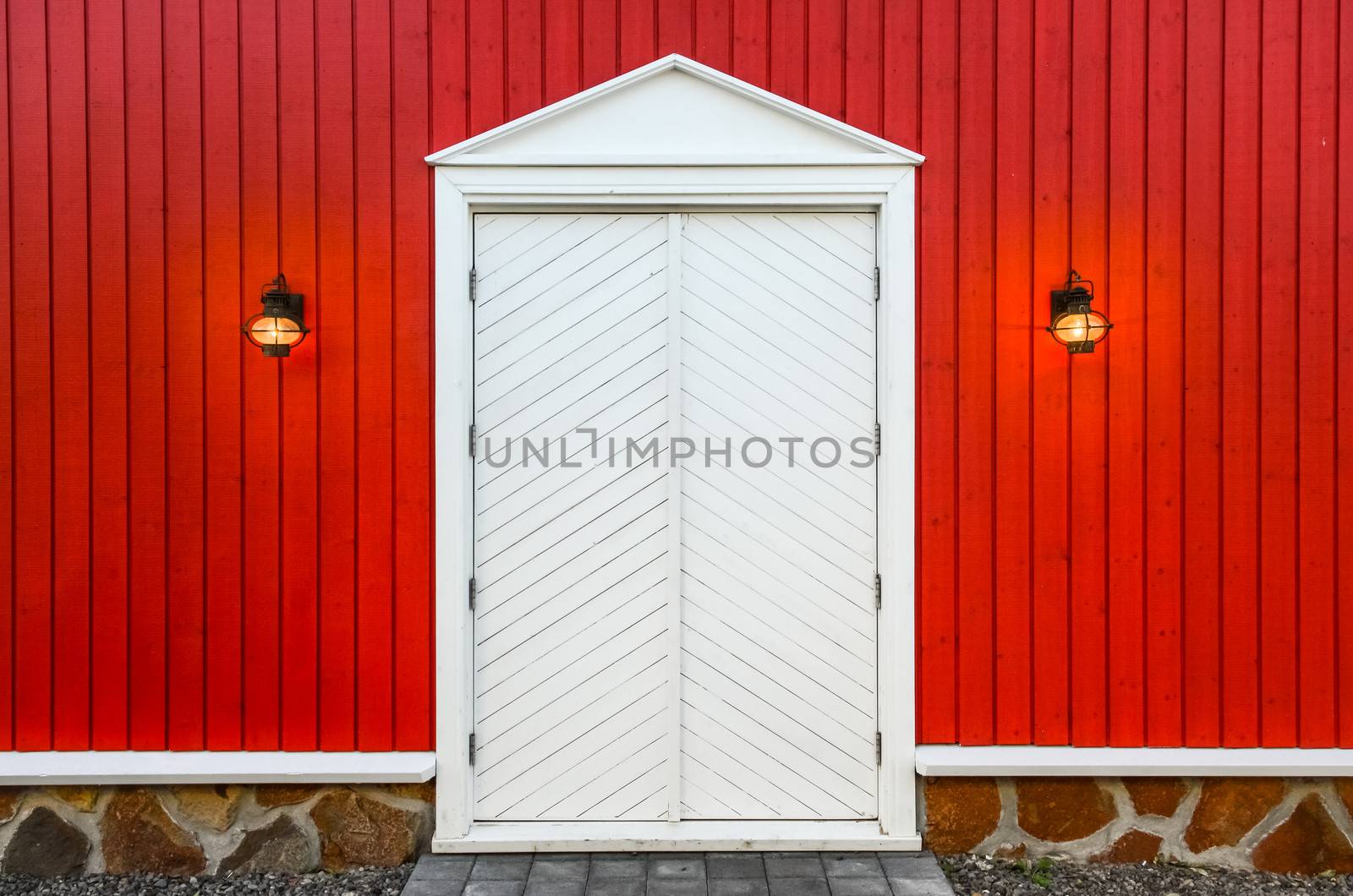 Red wooden wall and white doors with two porch lamps