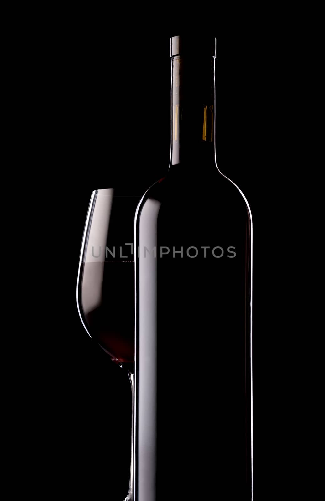 Glass and bottle of red wine on black background