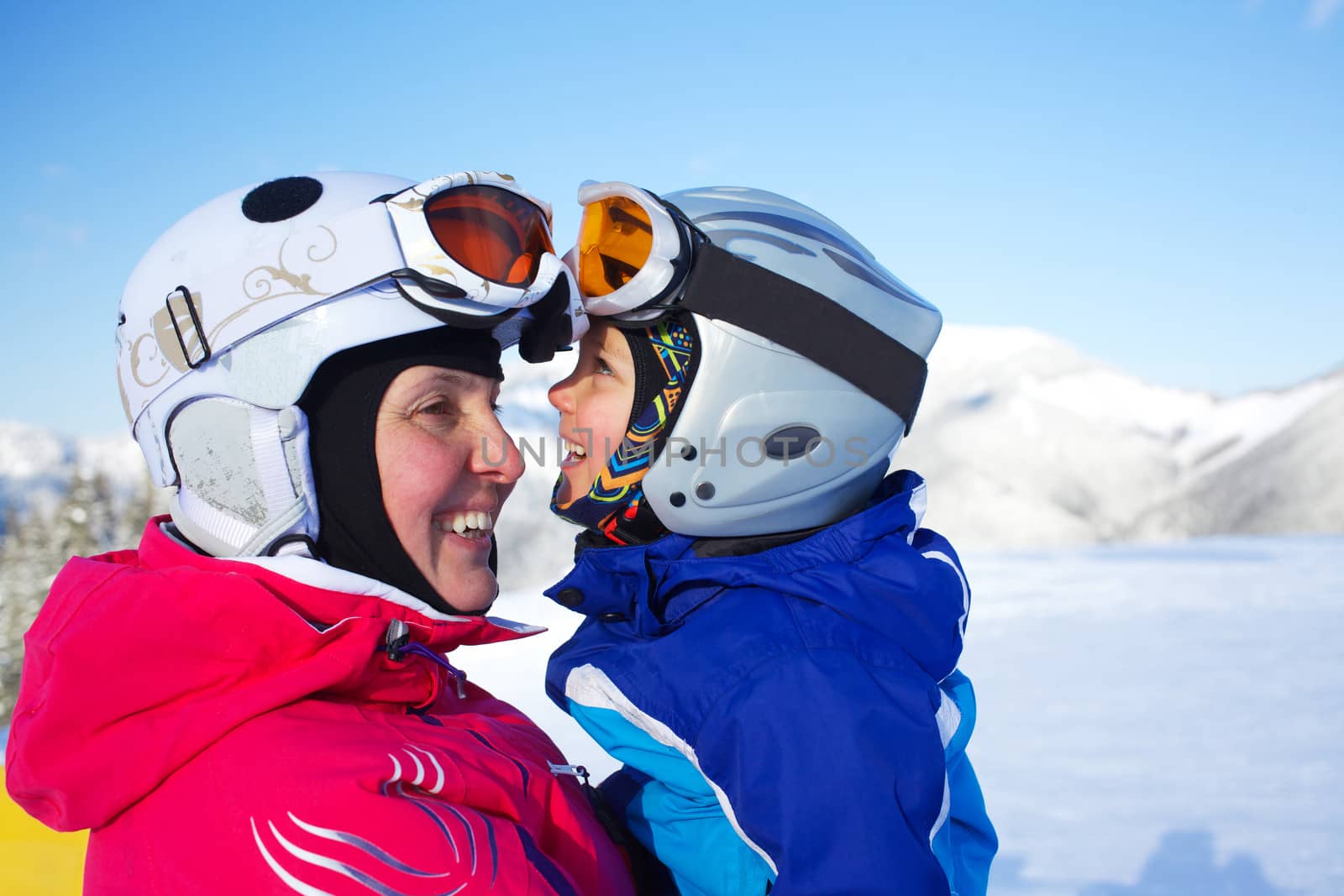 Happy little boy to ski in ski goggles and a helmet with his mother