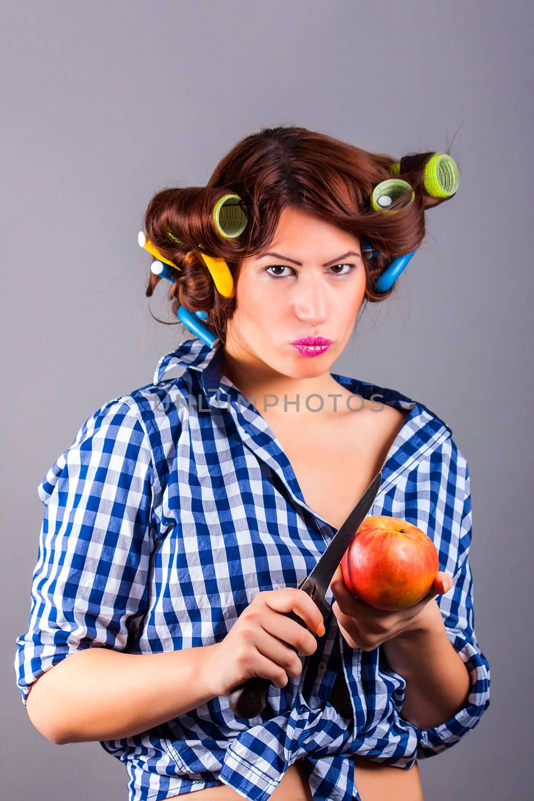 beautiful housewife with curlers holding apple and the knife