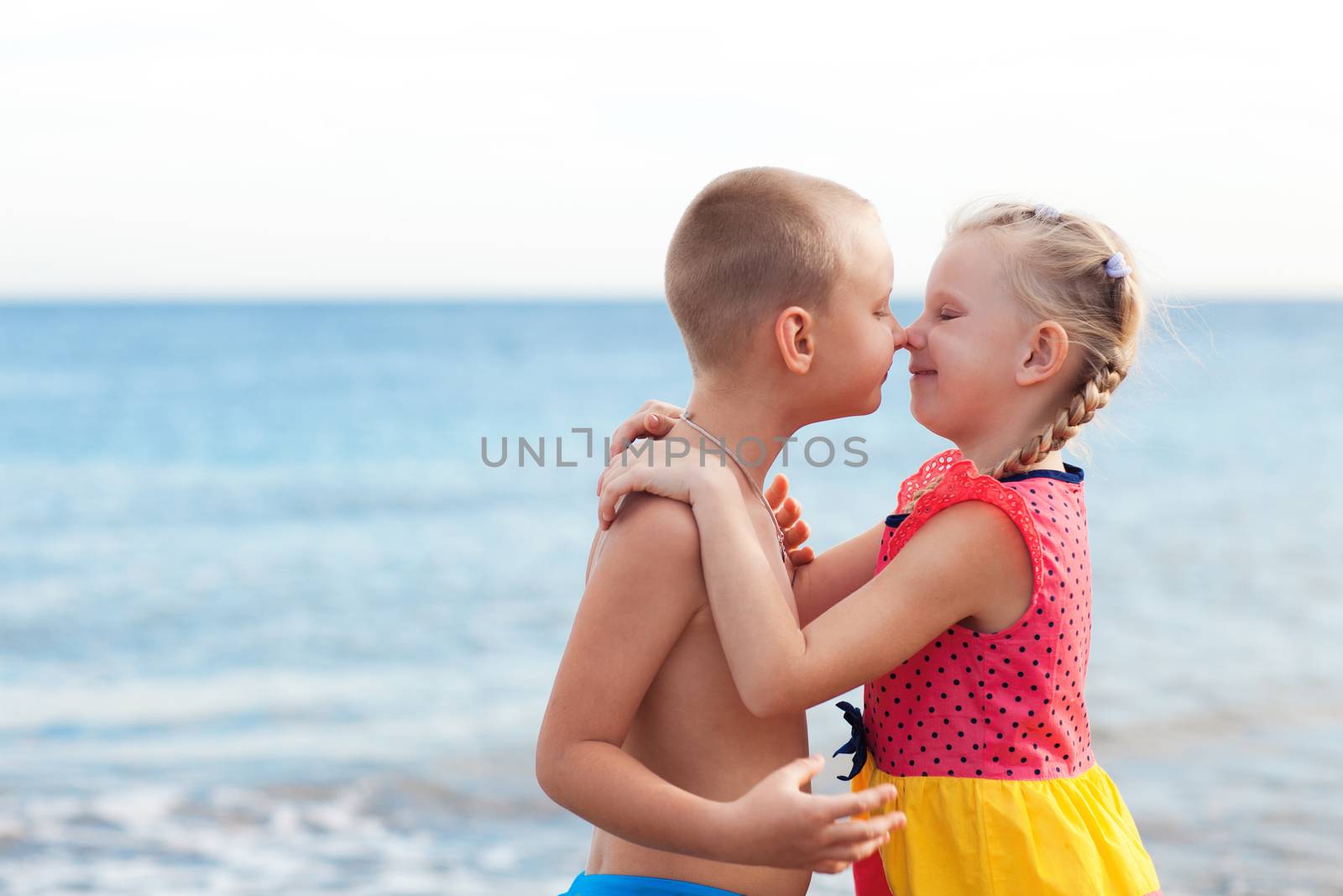 portrait of two children kissing on the beach