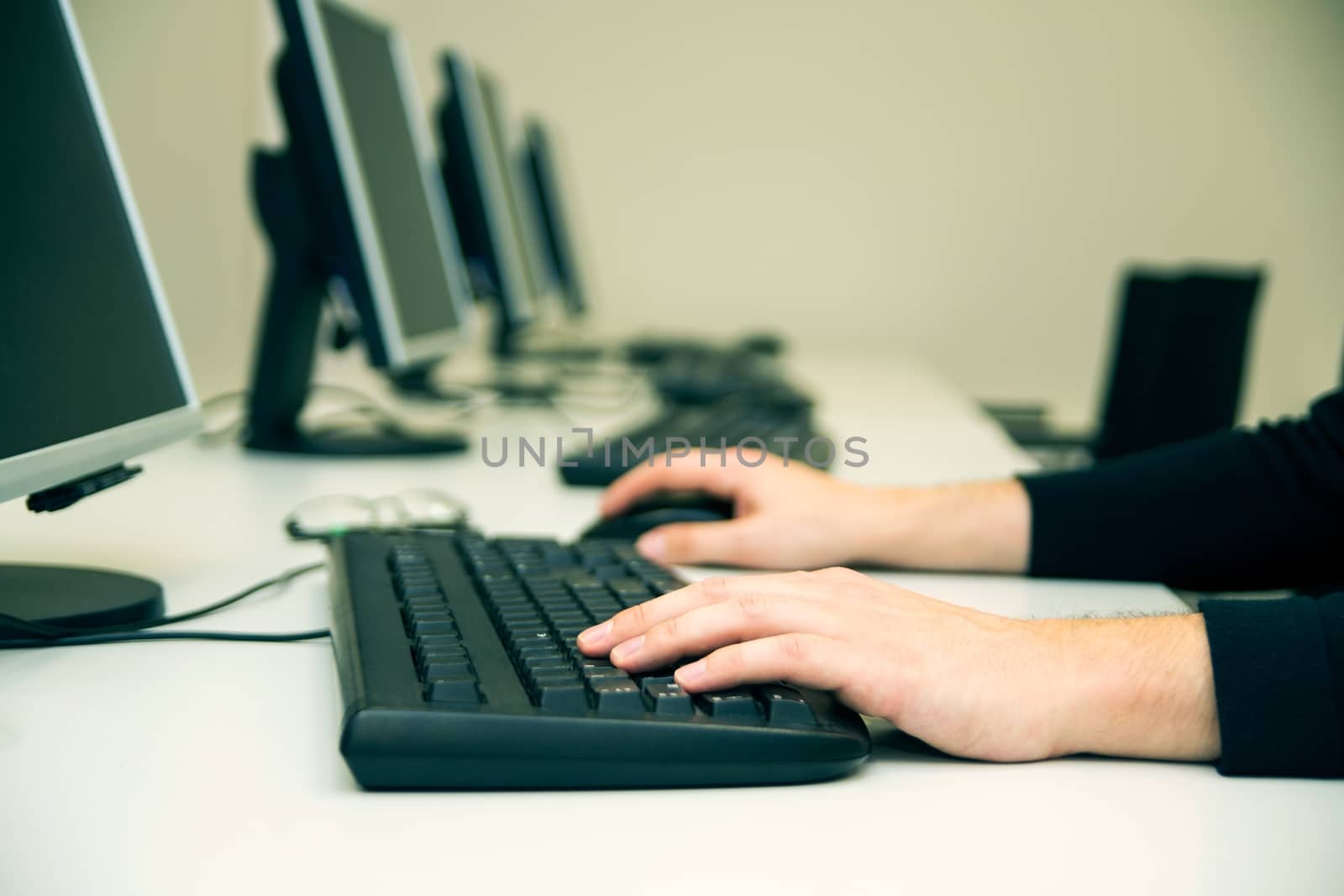 Young man typing on keyboard. Training room with computers by simpson33