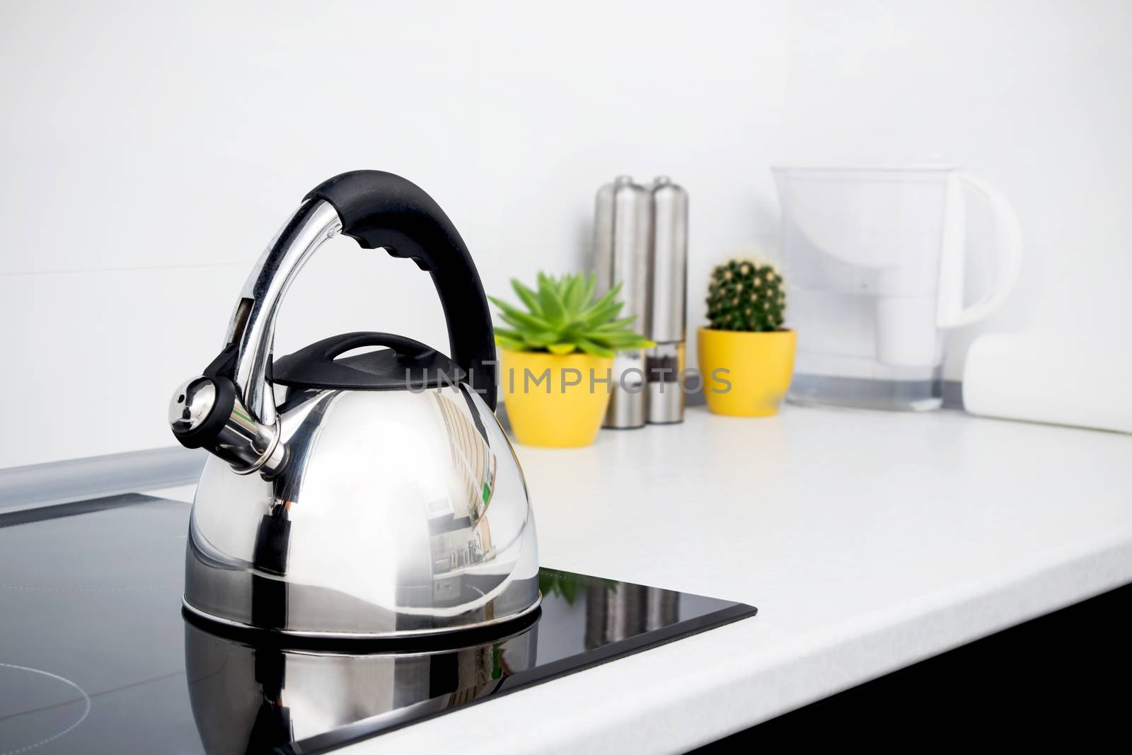 Steel kettle in modern kitchen with induction stove 