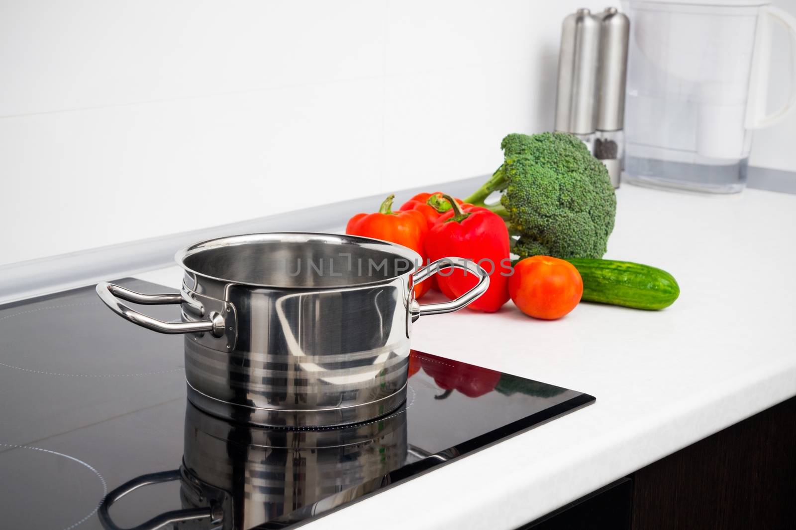 Pot and vegetables in modern kitchen with induction stove by simpson33