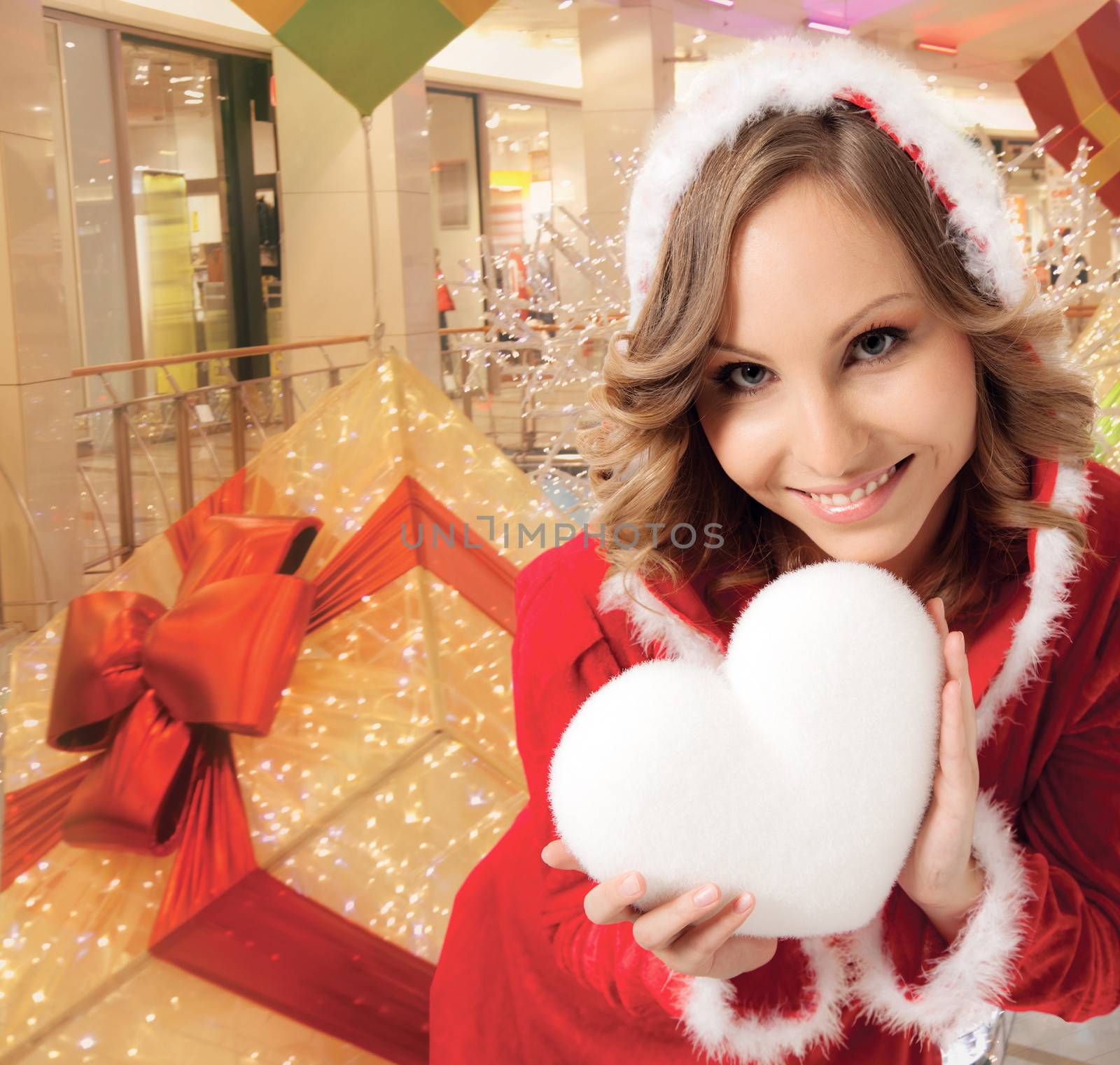 happy smiling Santa woman indoors, holding white heart, background digitally added, workpath