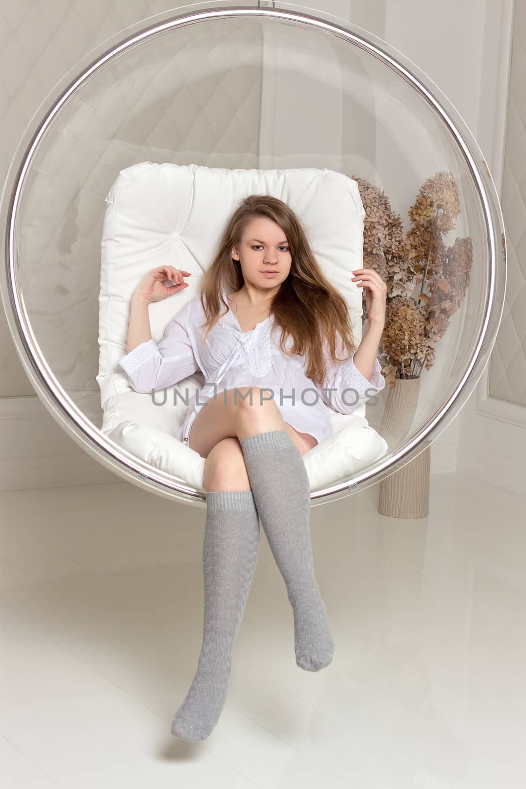 Girl in white tunic sitting in a chair suspended round