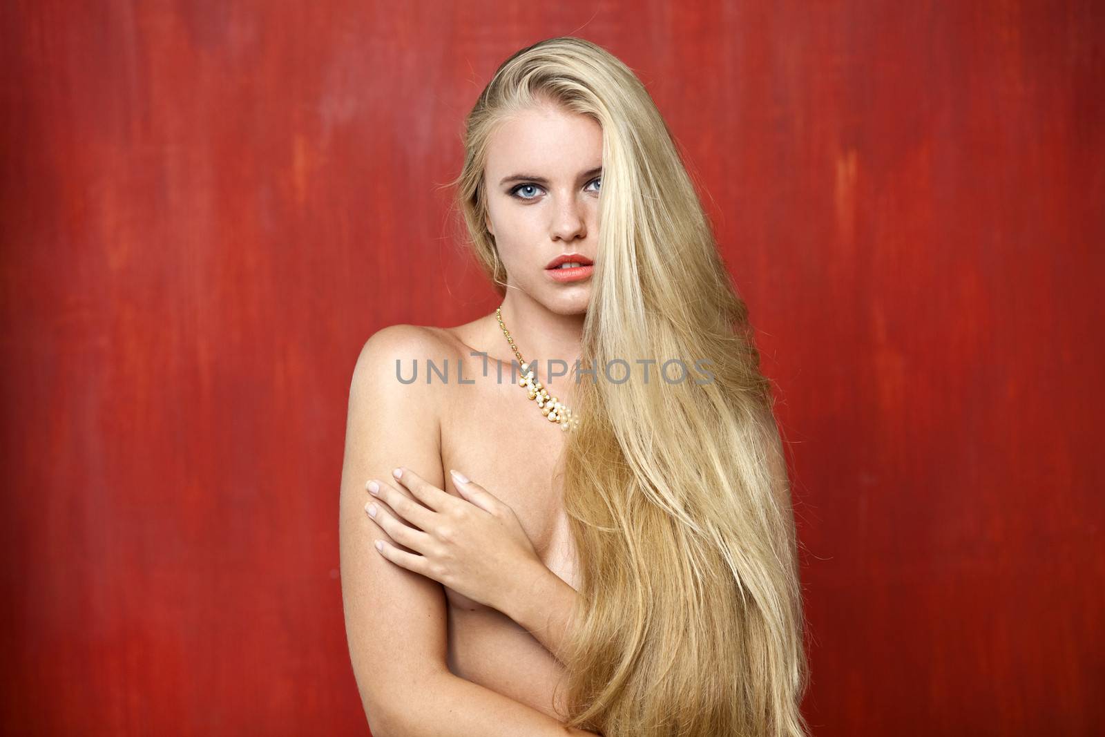 Sexy nude model on red wall studio