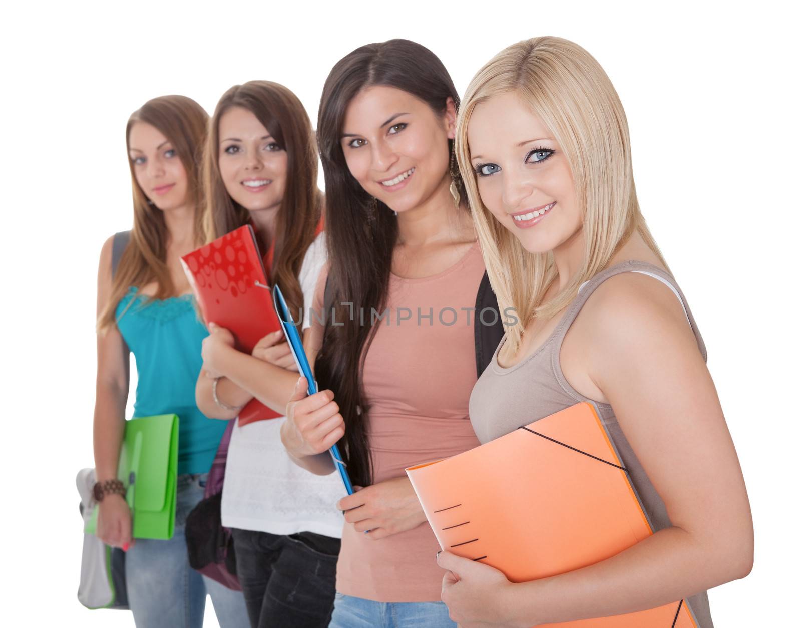 Four beautiful young female students standing in a receding row with folders of notes under their arms isolated on white