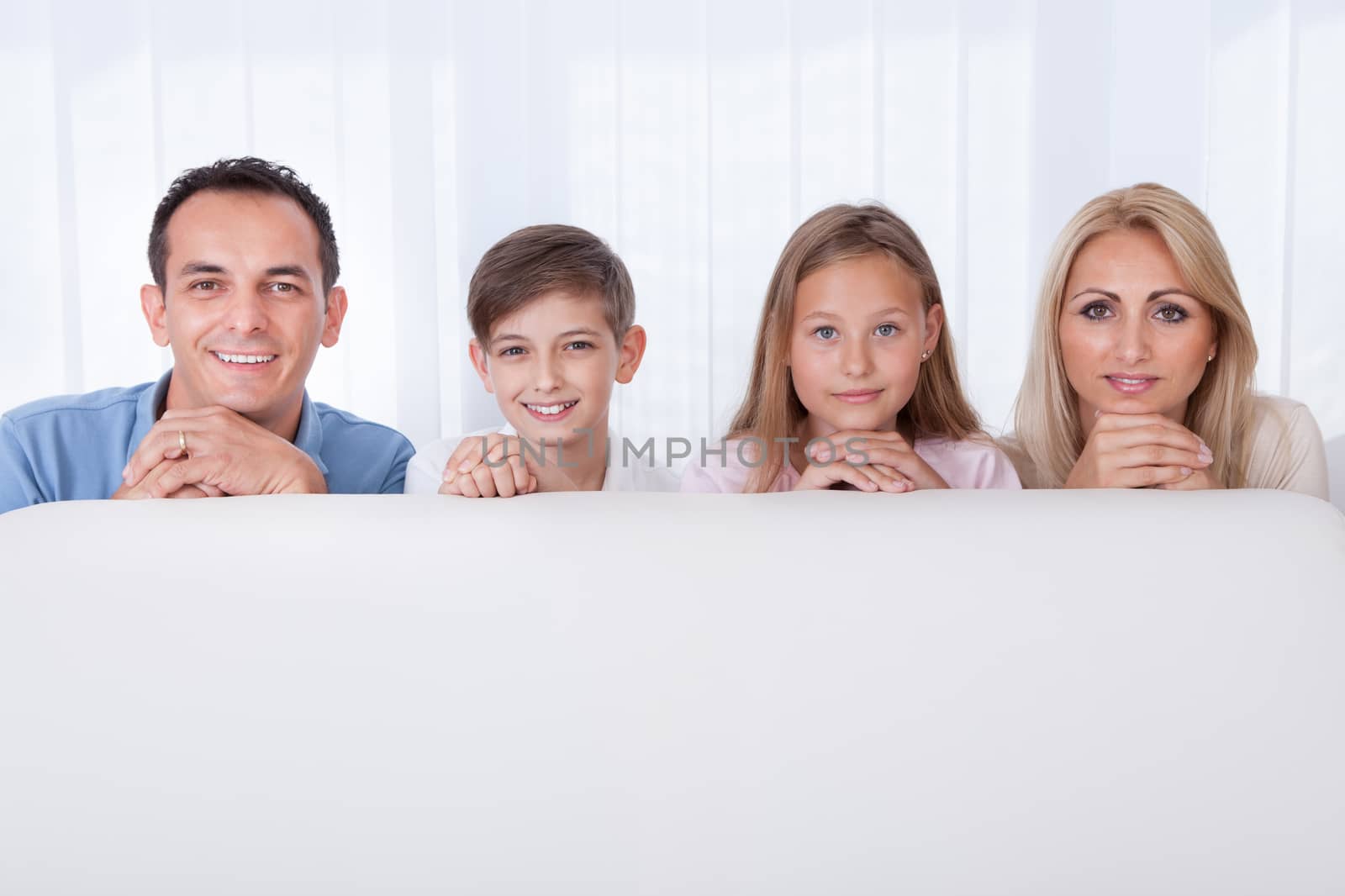 Portrait Of  Happy Family Behind White Sofa, Indoors