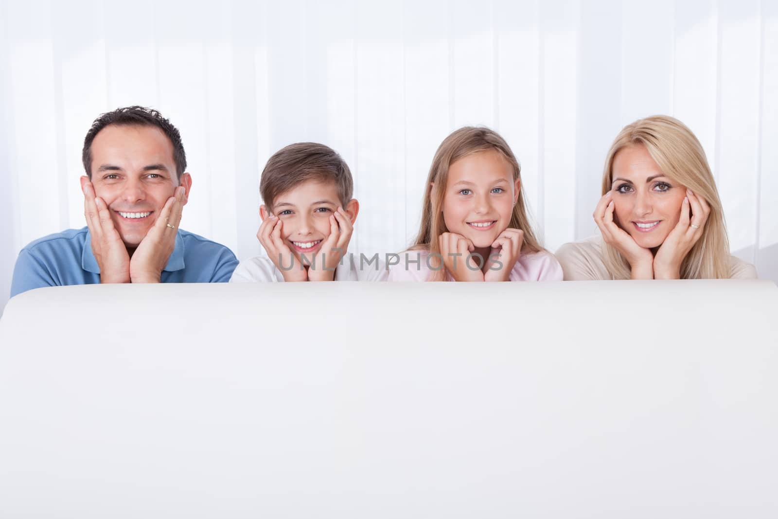 Portrait Of  Happy Family Behind White Sofa, Indoors