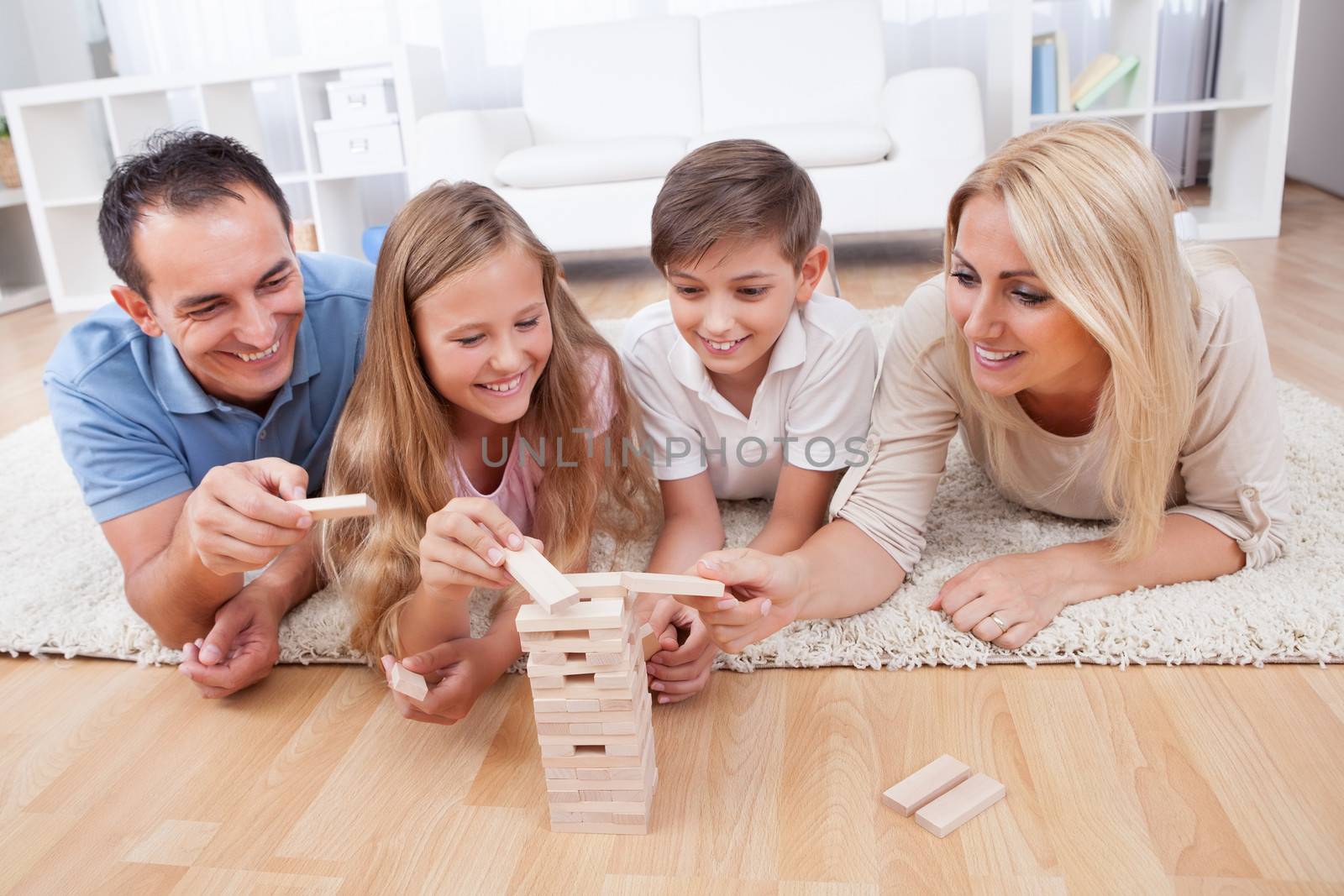 Happy Family Laying On Carpet Playing With The Wooden Blocks At Home