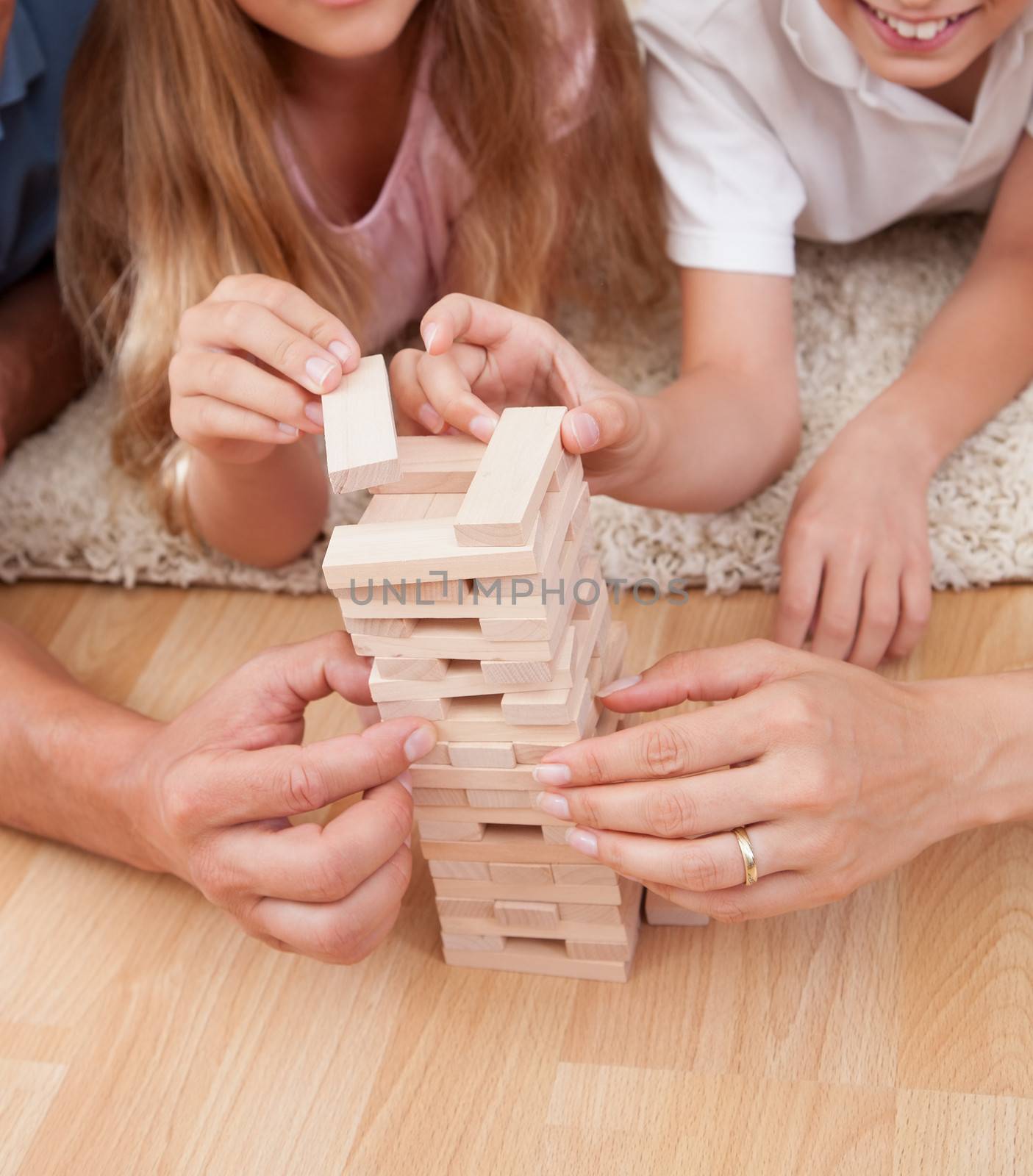 Happy Family Laying On Carpet Playing With The Wooden Blocks At Home