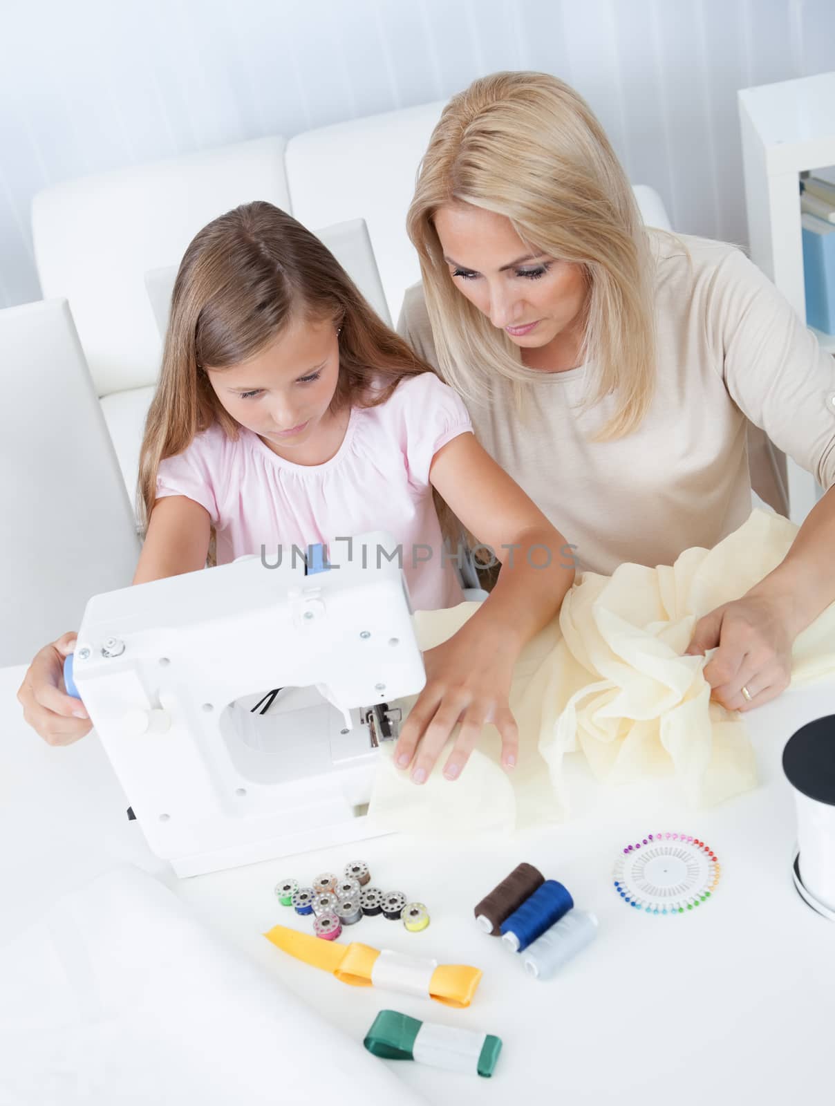 Portrait Of A Beautiful Young Girl Sewing With Her Mother At Home