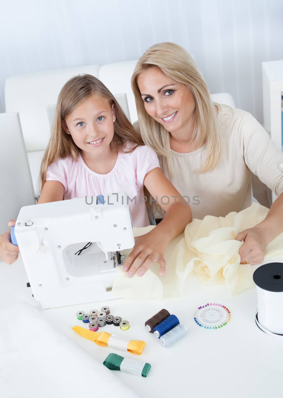 Portrait Of A Beautiful Young Girl Sewing With Her Mother At Home