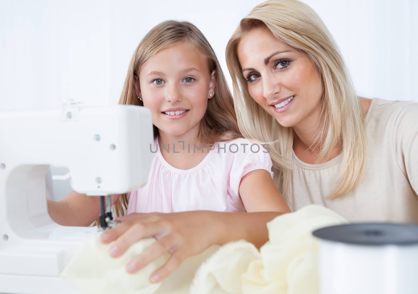 Portrait Of A Beautiful Young Girl Sewing With Her Mother At Home