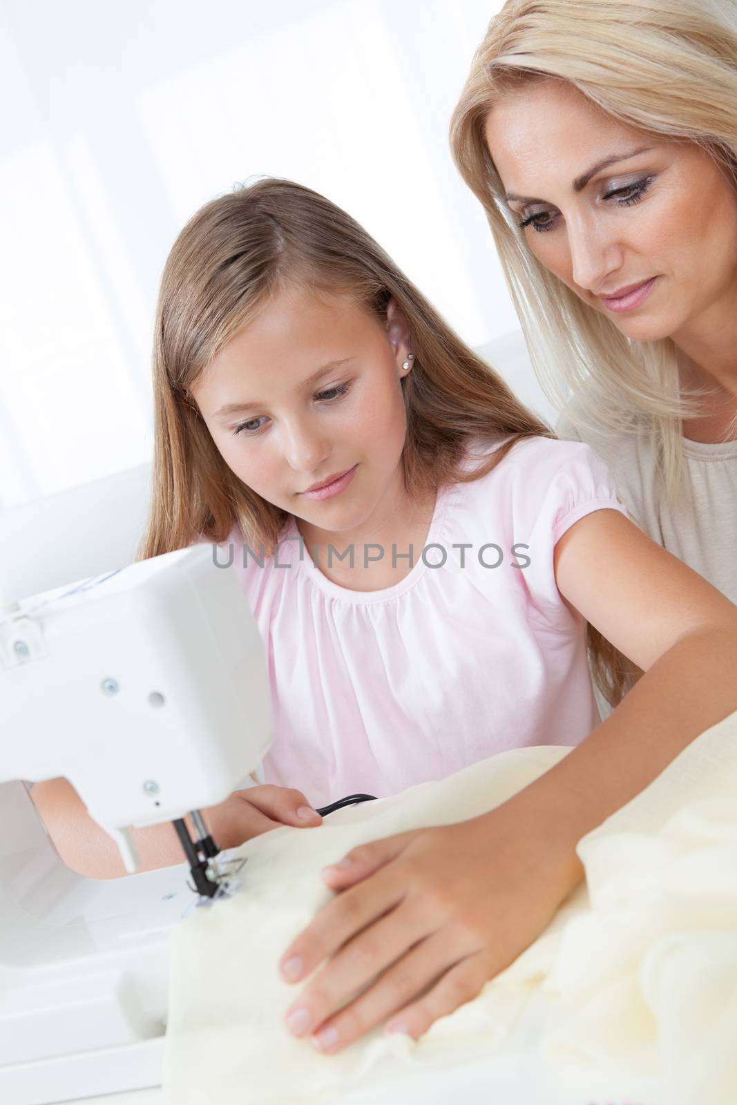 Portrait Of A Beautiful Young Girl Sewing With Her Mother At Home