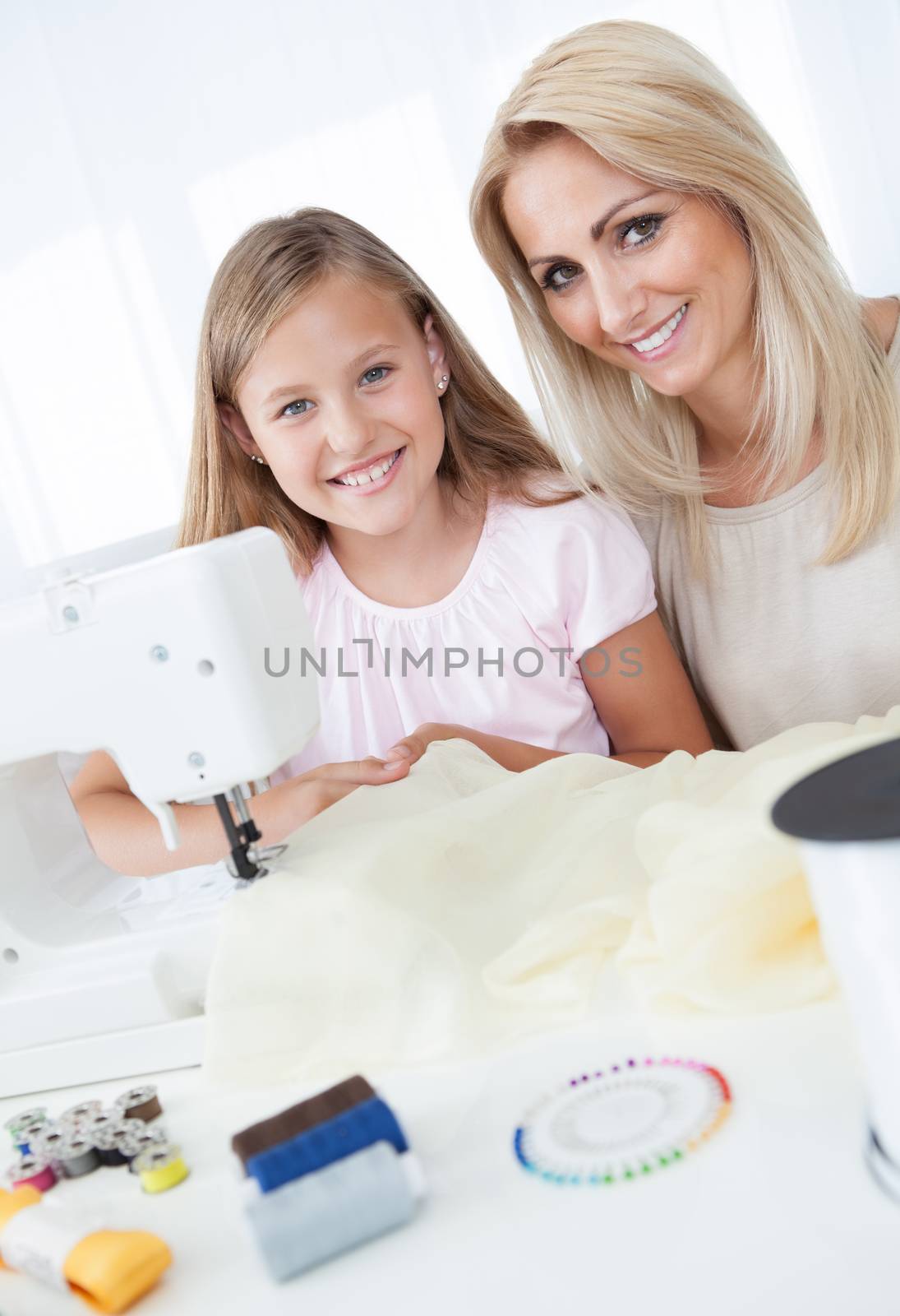 Portrait Of A Beautiful Young Girl Sewing With Her Mother At Home