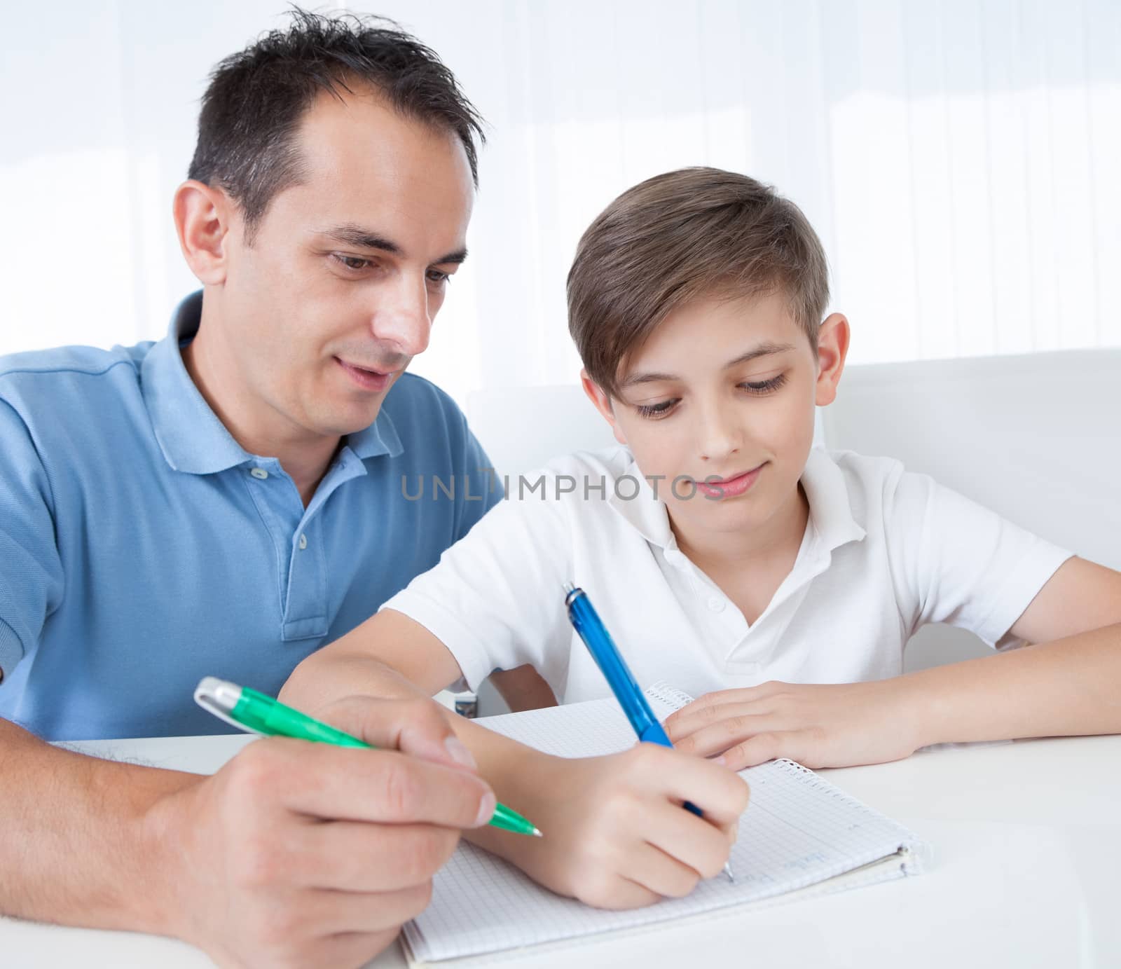 Portrait Of Father And Son Doing Homework At Home