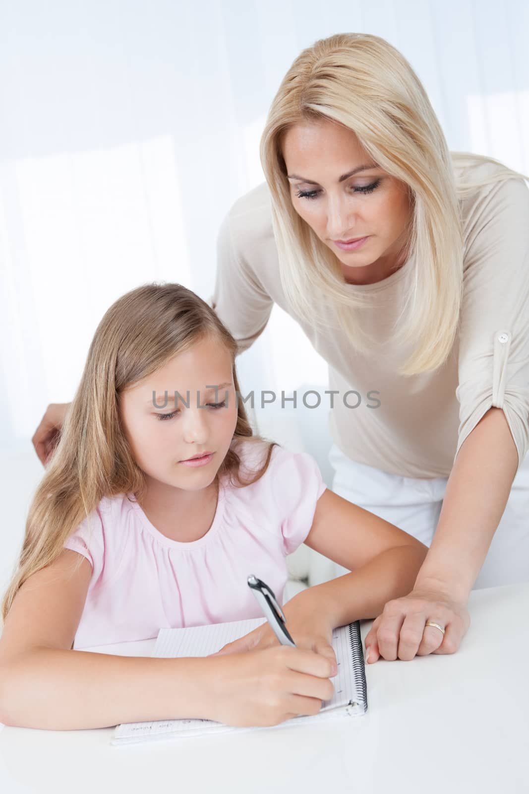 Teacher Helping Girl With Exercise At School