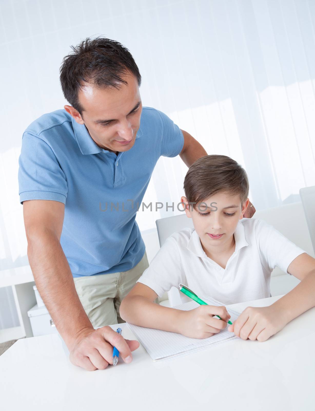 Teacher Helping Boy With Exercise At School